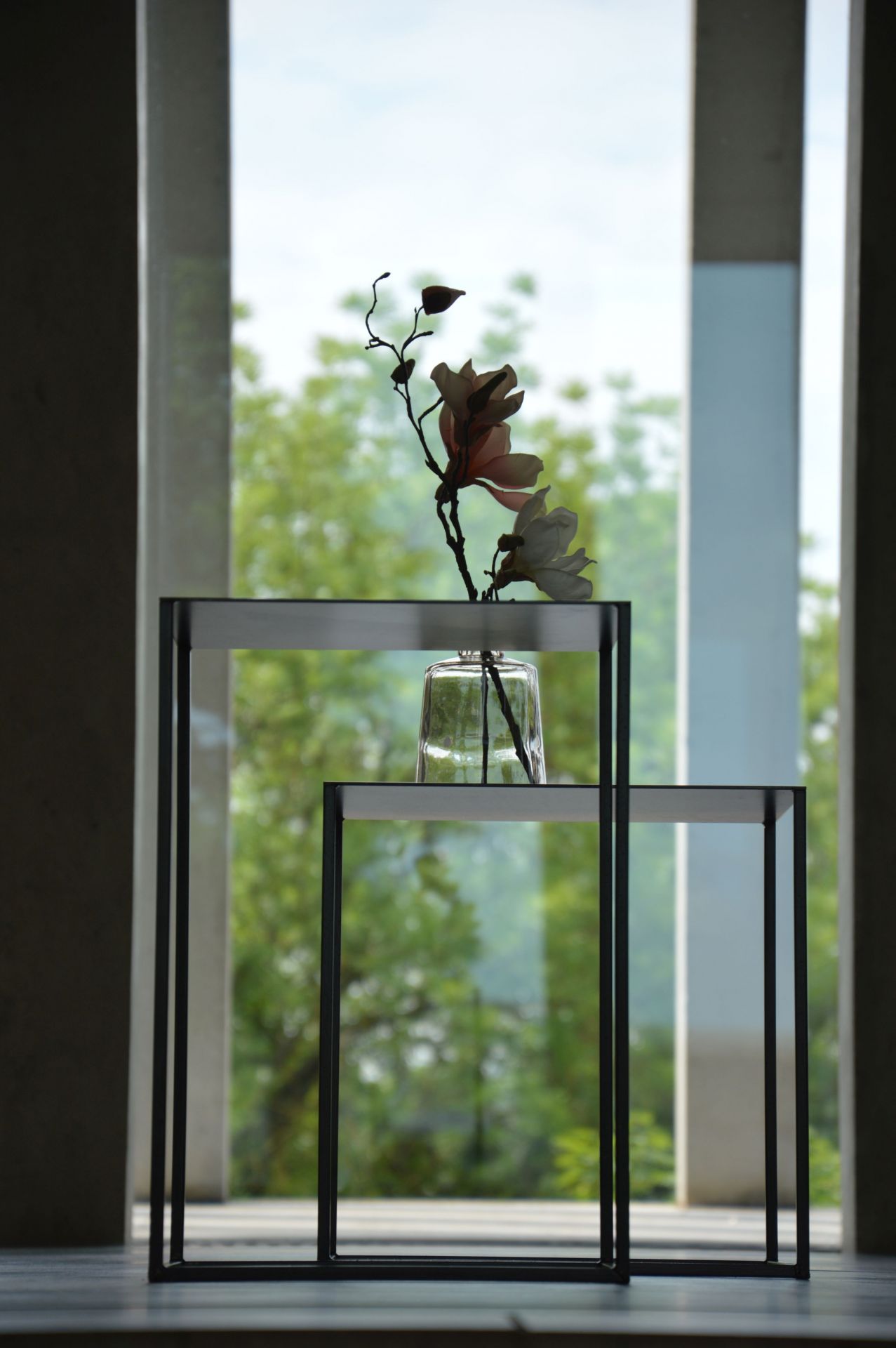 Pur Beistelltisch von Jan Kurtz: Zwei schwarze, minimalistische Tische mit Blume in Glasvase.