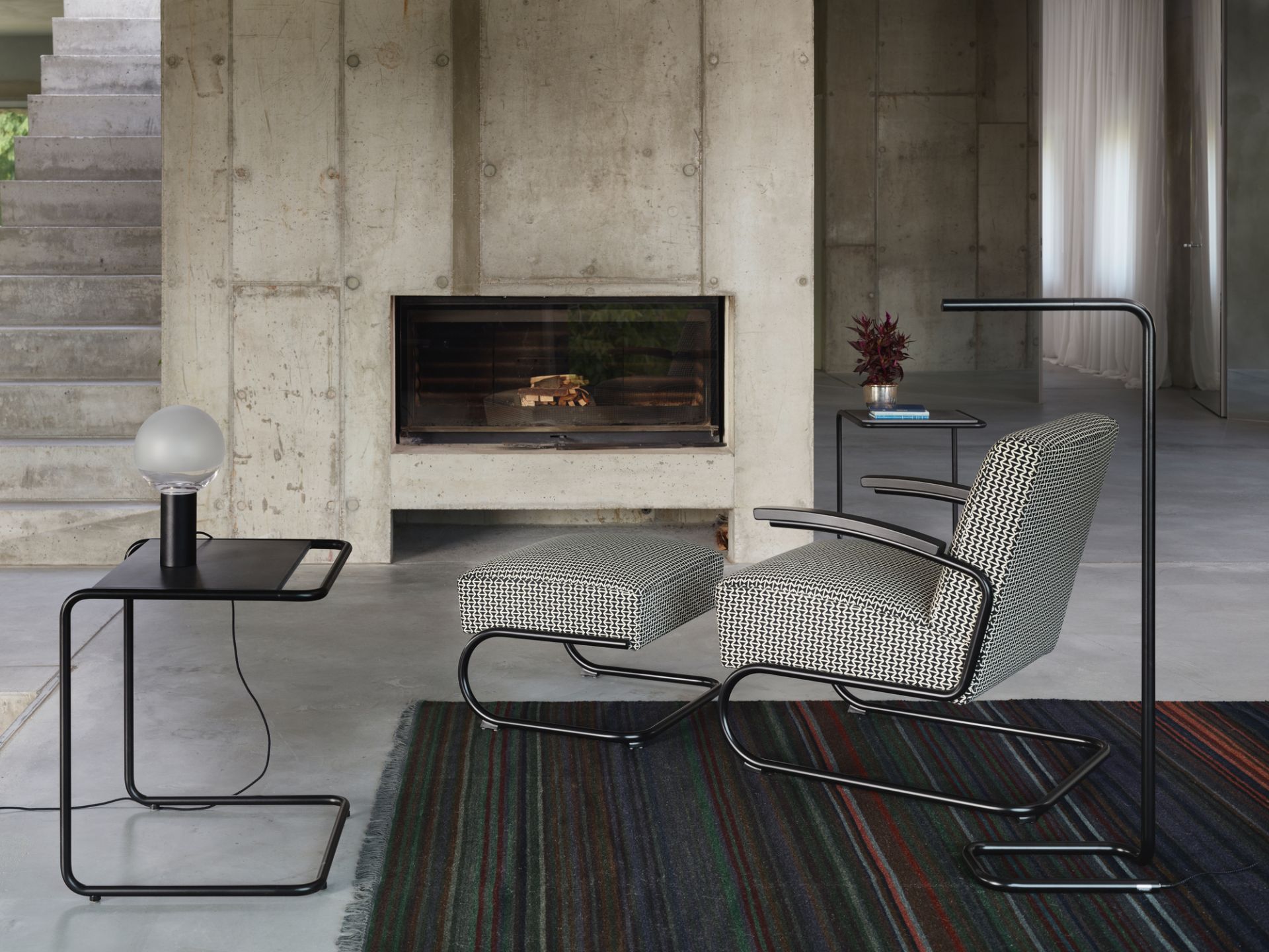 Schwarzer B97 a Thonet Beistelltisch im Bauhaus-Stil neben Sessel und Lampe im Wohnzimmer.