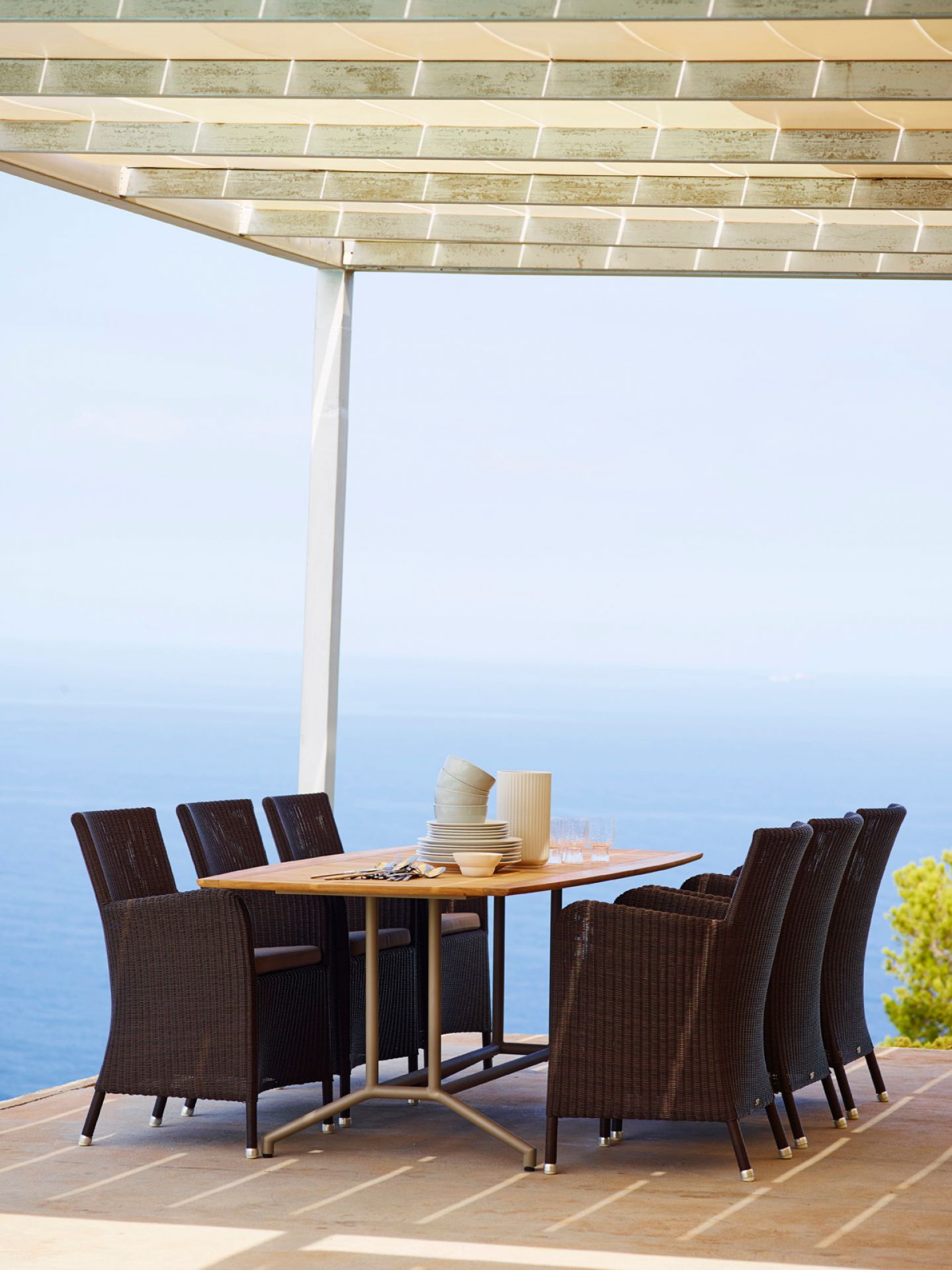 Esstisch mit schwarzen Cane-Line Outdoor Sesseln aus Rattan vor Meerblick. Gartenmöbel für Terrasse.