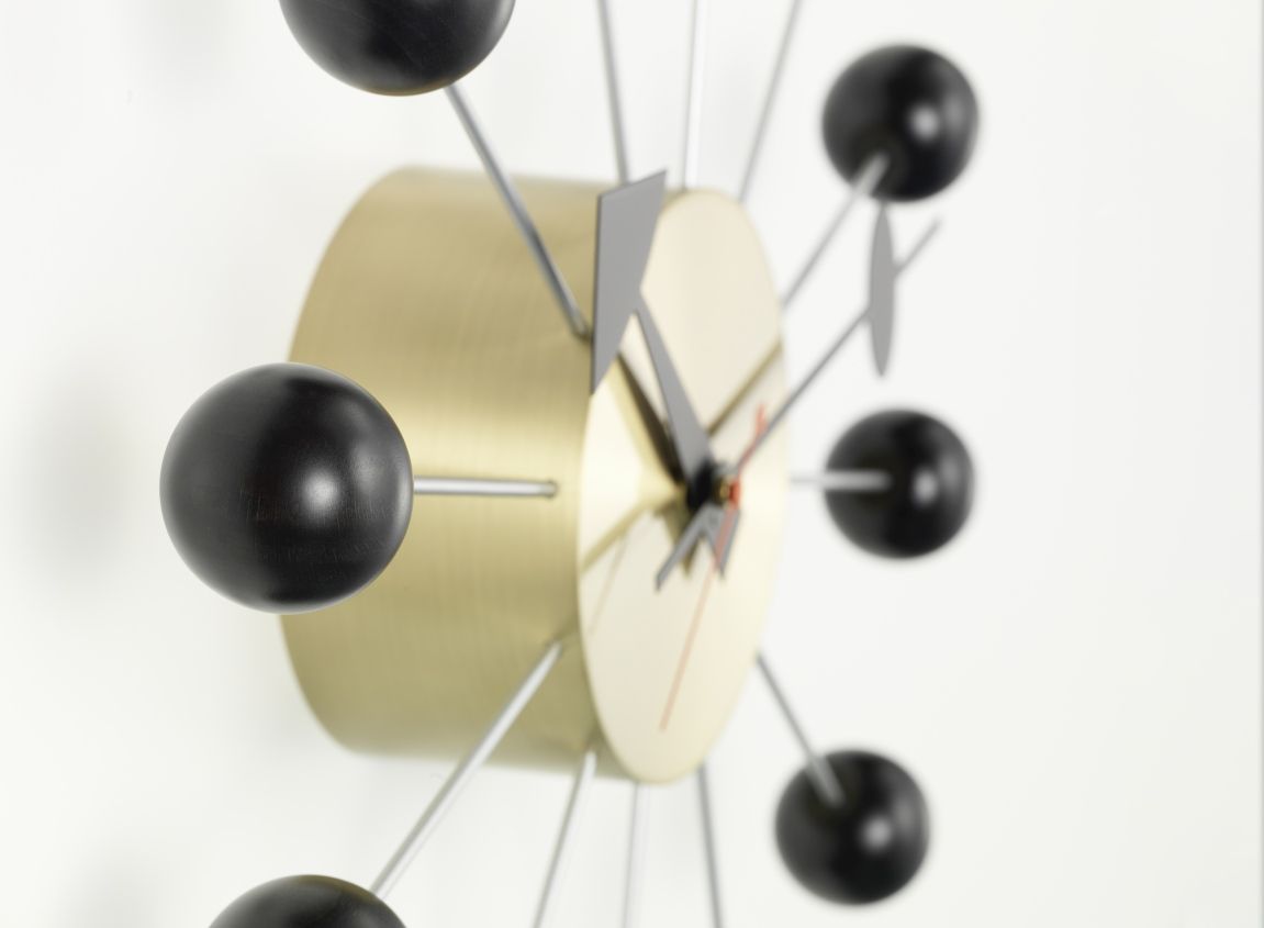 Detailaufnahme der Vitra Ball Clock Wanduhr in Schwarz mit goldenem Gehäuse.