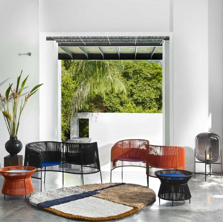 Caribe Vis a Vis Bank in Orange, Rosa und Gelb mit Outdoor-Möbeln und Teppich.