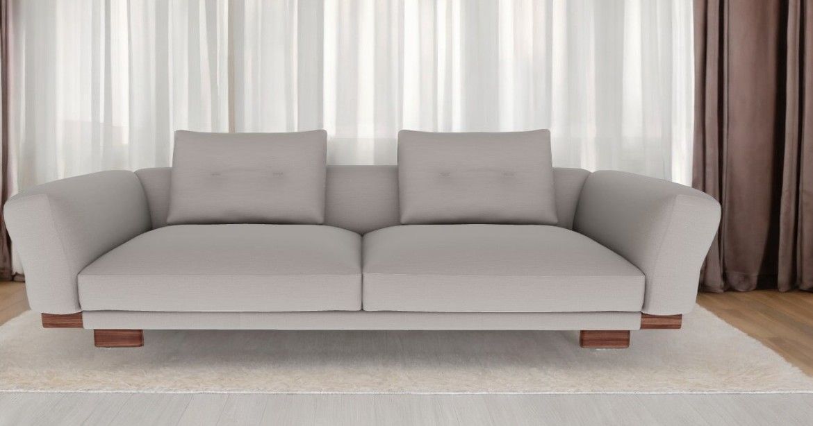 Helles Sengu Sofa von Cassina mit zwei Kissen und Holzfüßen vor Vorhängen.