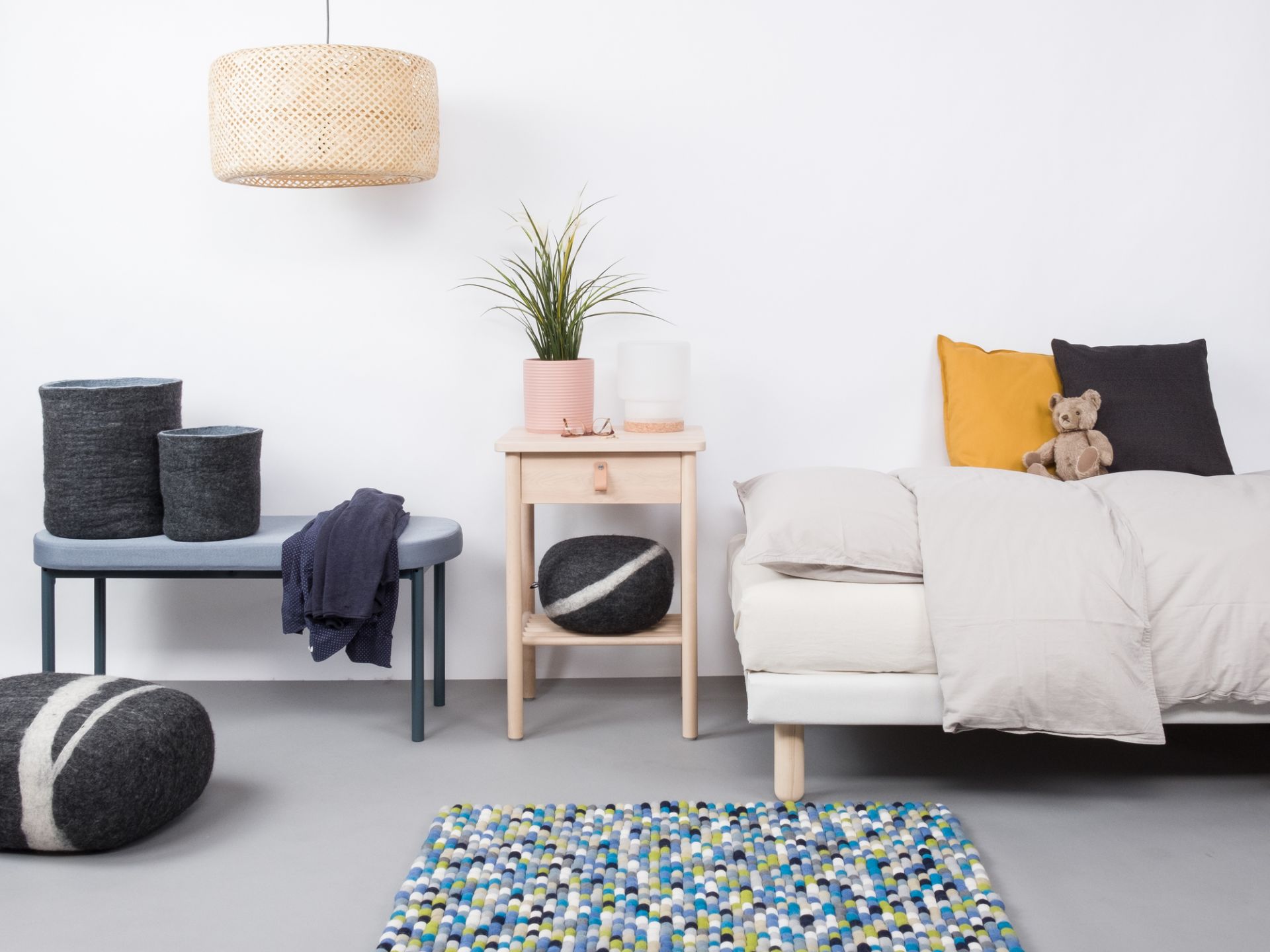 Myfelt Filzkugel Teppich 140x200 cm im Schlafzimmer mit Bett und Dekoration.