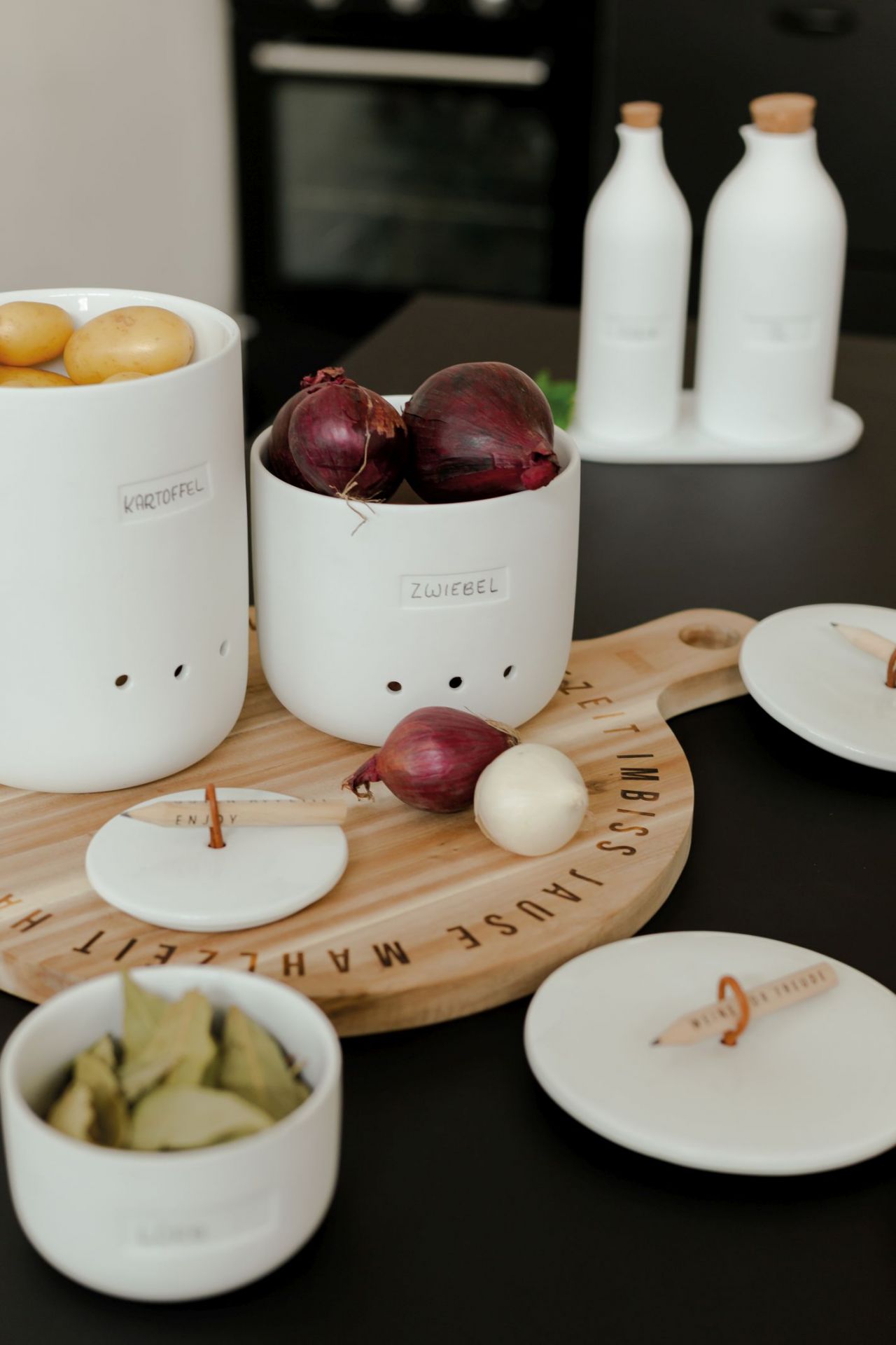 Weine vor Freude Aufbewahrungstöpfe für Kartoffeln und Zwiebeln, stilvolle Küchenaufbewahrung aus Keramik auf Schneidebrett.