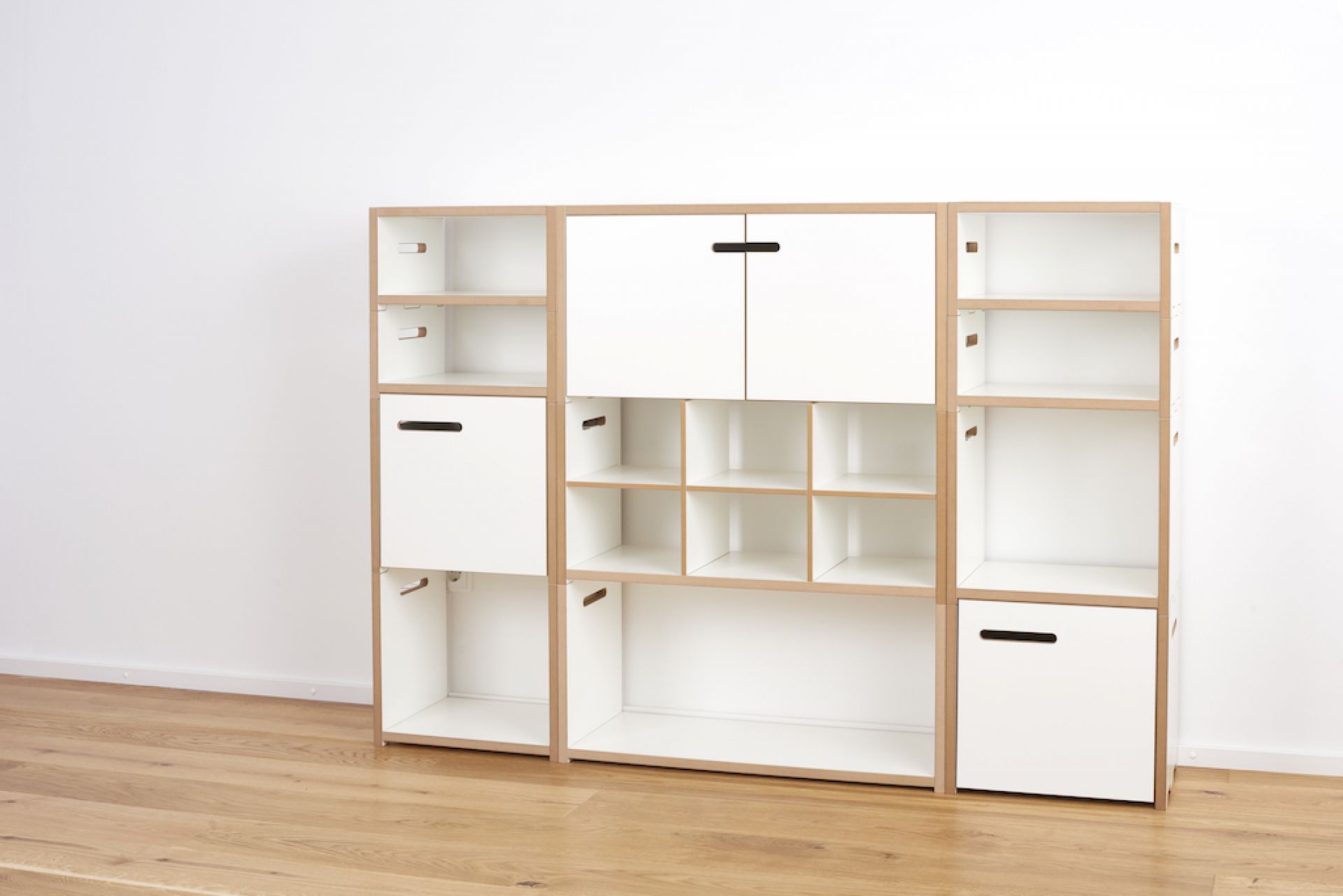 Tojo Halbstark Regalsystem: Weißes, modulares Regal mit Fächern, Schubladen und Türen aus Holz.