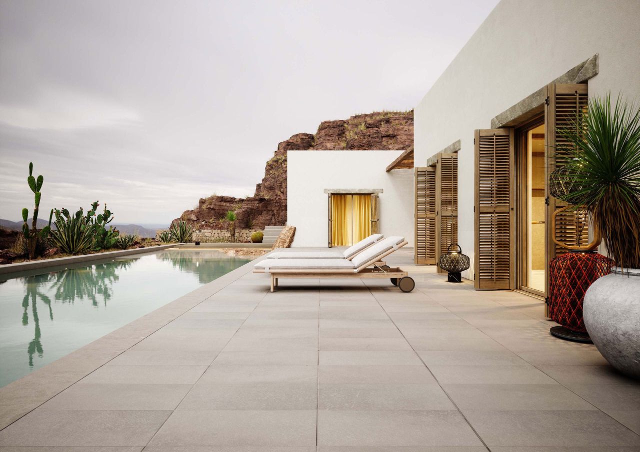 Zwei Dedon Tibbo Sonnenliegen mit Polster am Pool eines modernen Hauses mit mediterranem Flair.