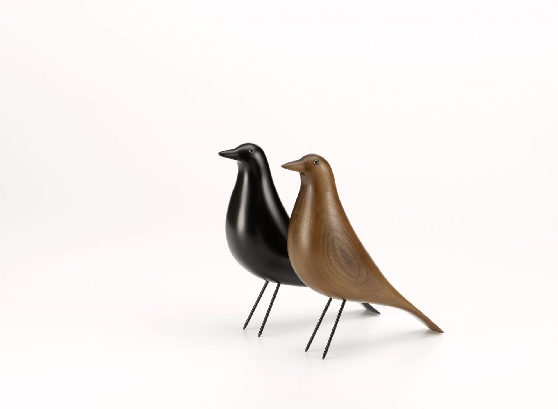 Zwei Eames House Bird Skulpturen, eine aus schwarzem Holz, eine aus Nussbaumholz, von Vitra.