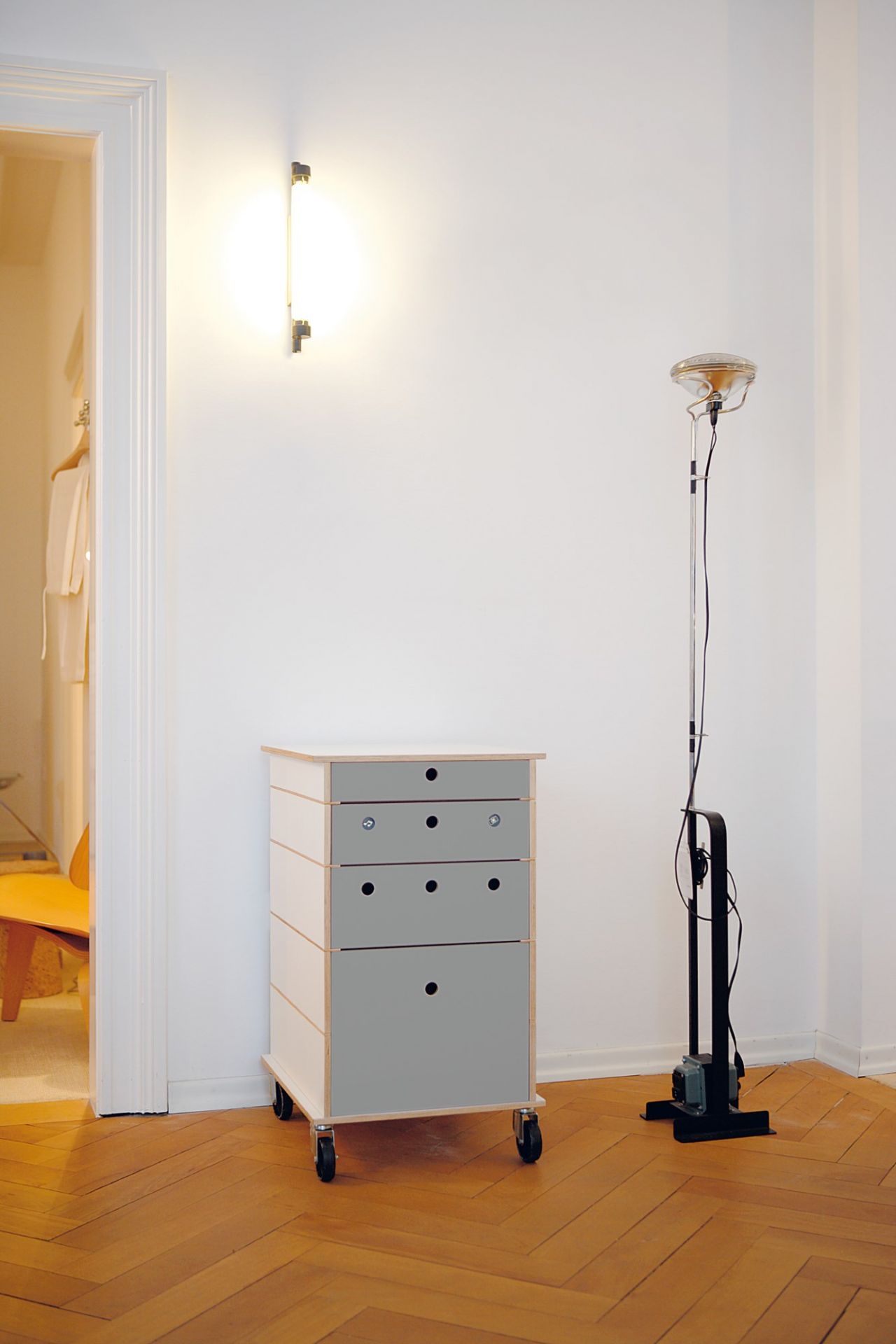 Nils Holger Moormann Lader Schubkastensystem mit grauen Schubladen und Rollen auf Parkettboden.