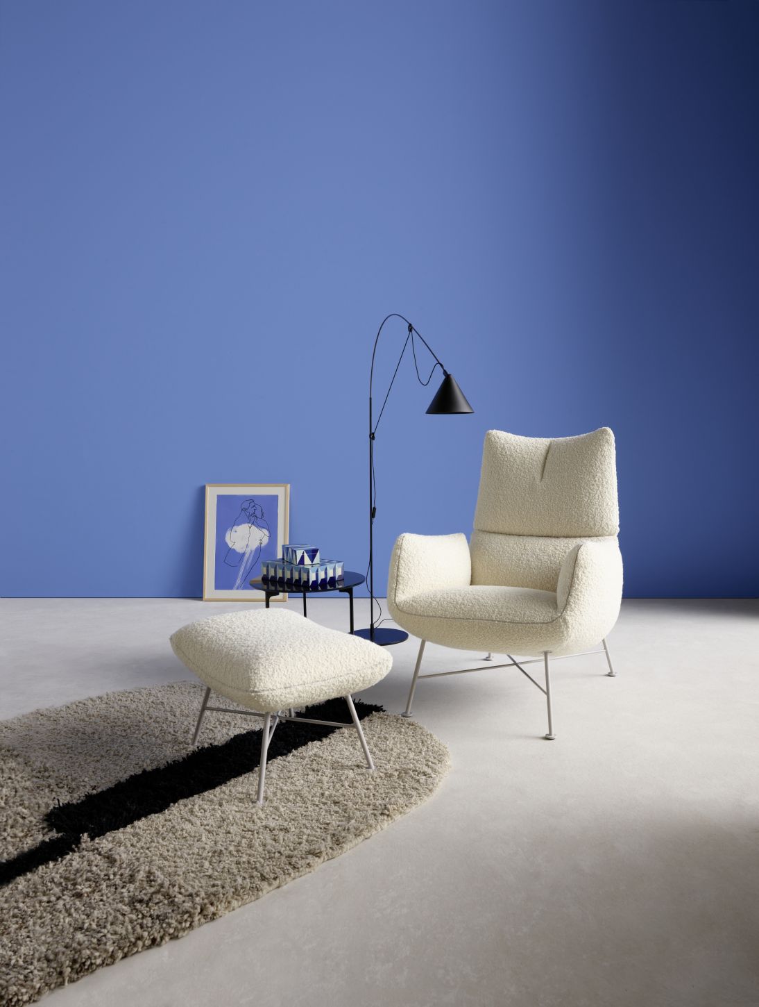 Jalis Lounge Hocker mit Drahtgestell in Creme, passend zum Sessel, auf einem Teppich.