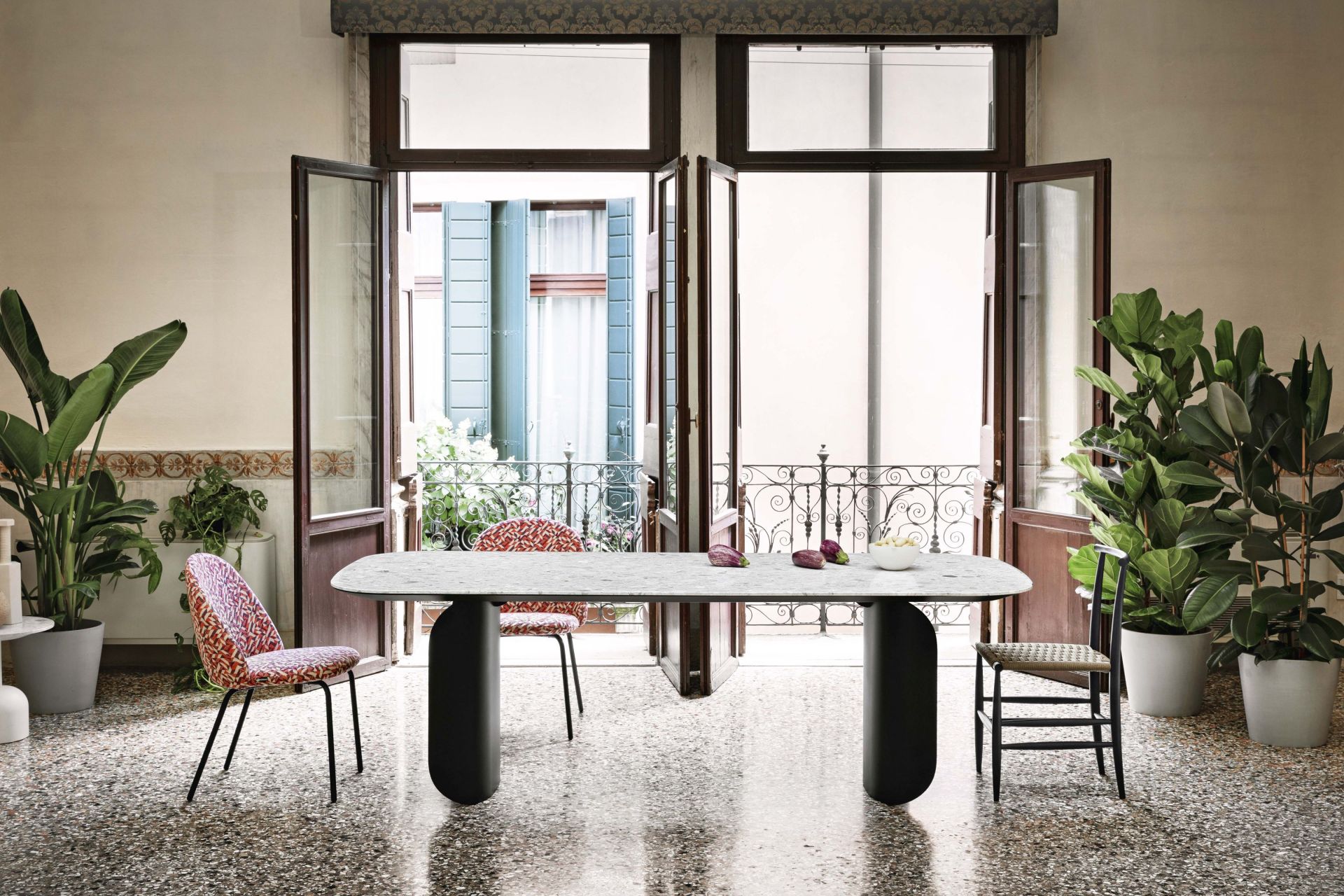 Barry Palladio Moro Marmortisch von Miniforms in einem hellen Raum mit Stühlen und Pflanzen.