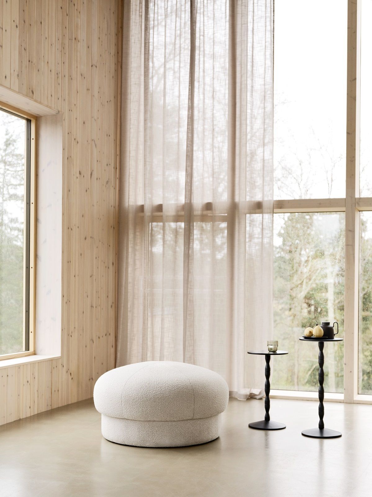 Weißer Uno Pouf Hocker von Design House Stockholm im hellen Raum mit Holzwand und Fenstern.