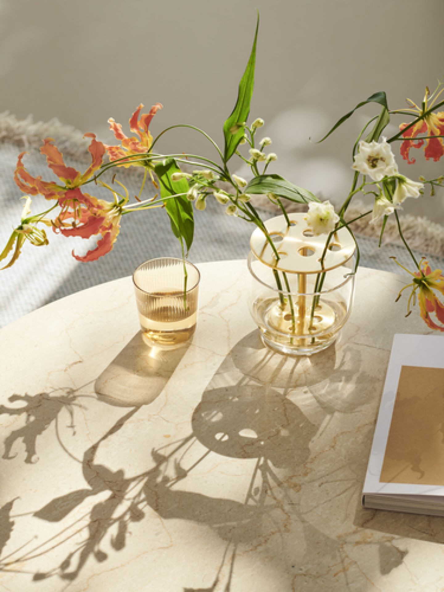 Detailaufnahme: Fritz Hansen Couchtisch mit Blumen, Vase und Buch im hellen, modernen Wohnzimmer.