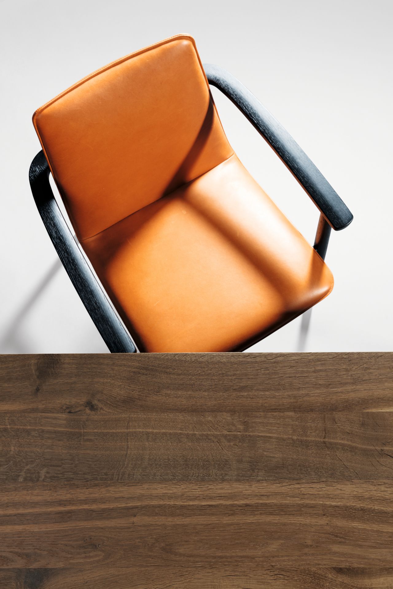 Detailaufnahme Janua S 600 Tisch Eiche geräuchert, Tischplatte aus Massivholz mit Stuhl im Hintergrund.