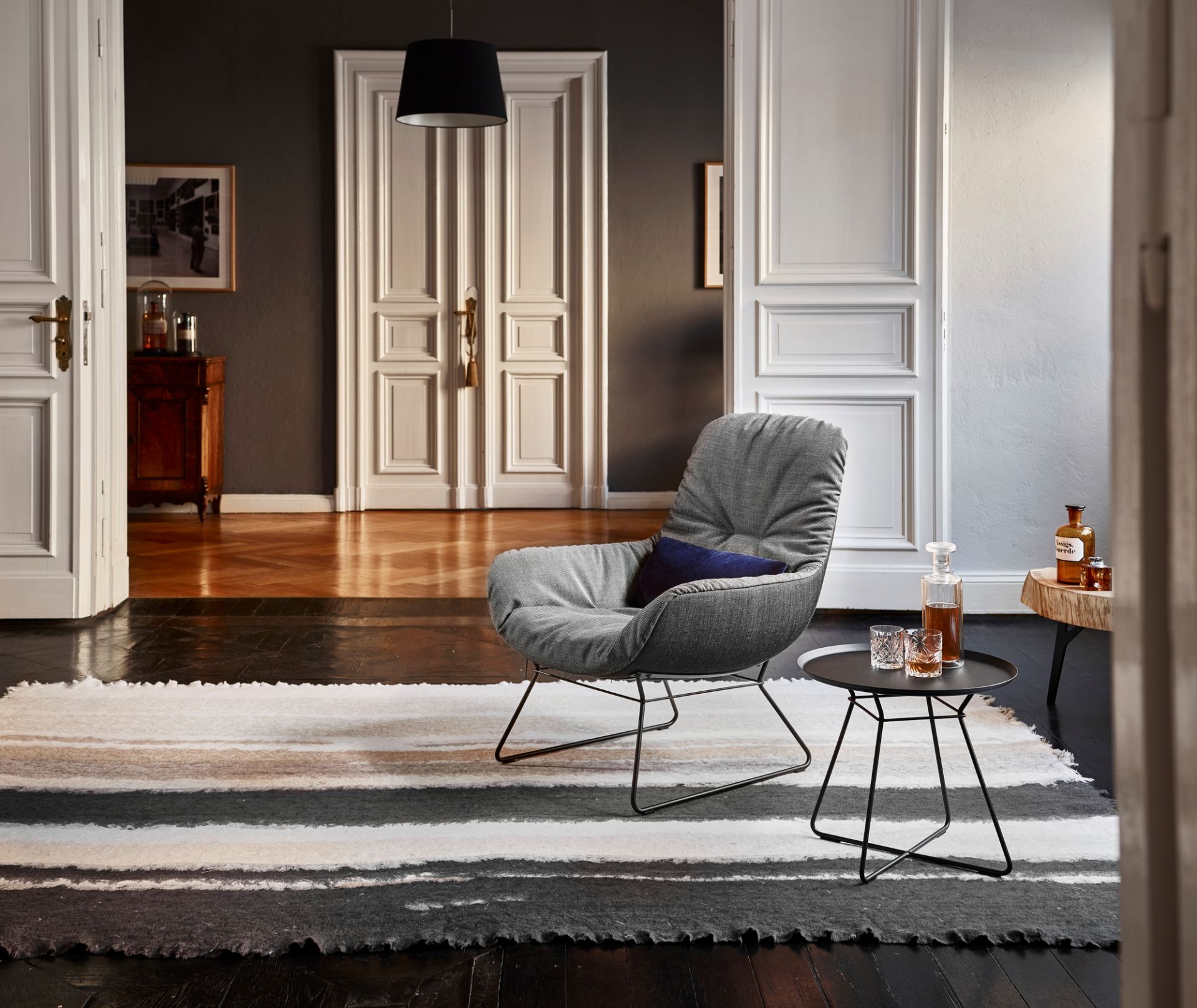 Leya Small Beistelltisch von Freifrau Manufaktur neben Sessel mit Getränken im stilvollen Wohnzimmer.