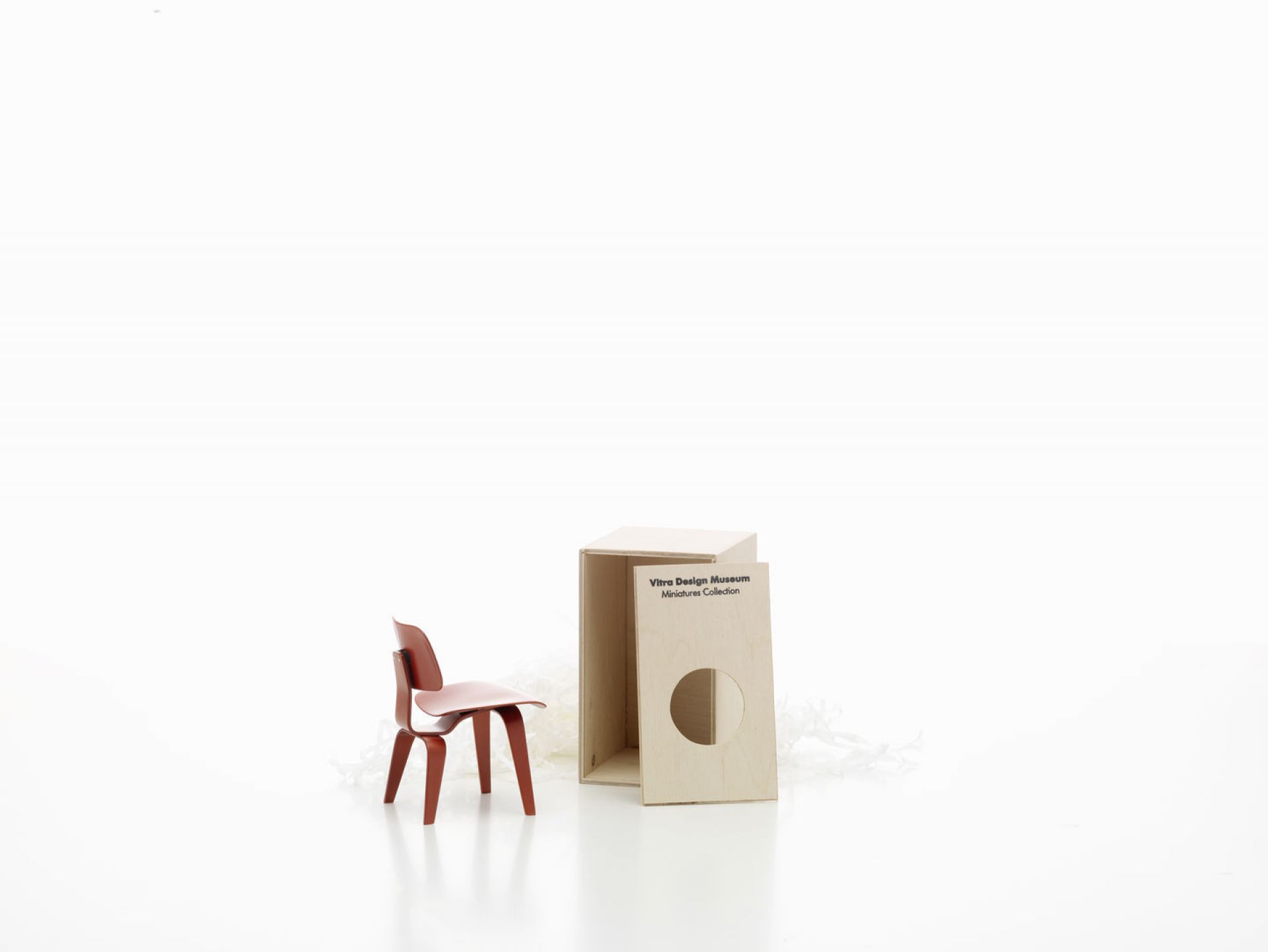 Roter DCW Miniatur Stuhl von Vitra neben der Verpackung aus der Miniatures Collection.