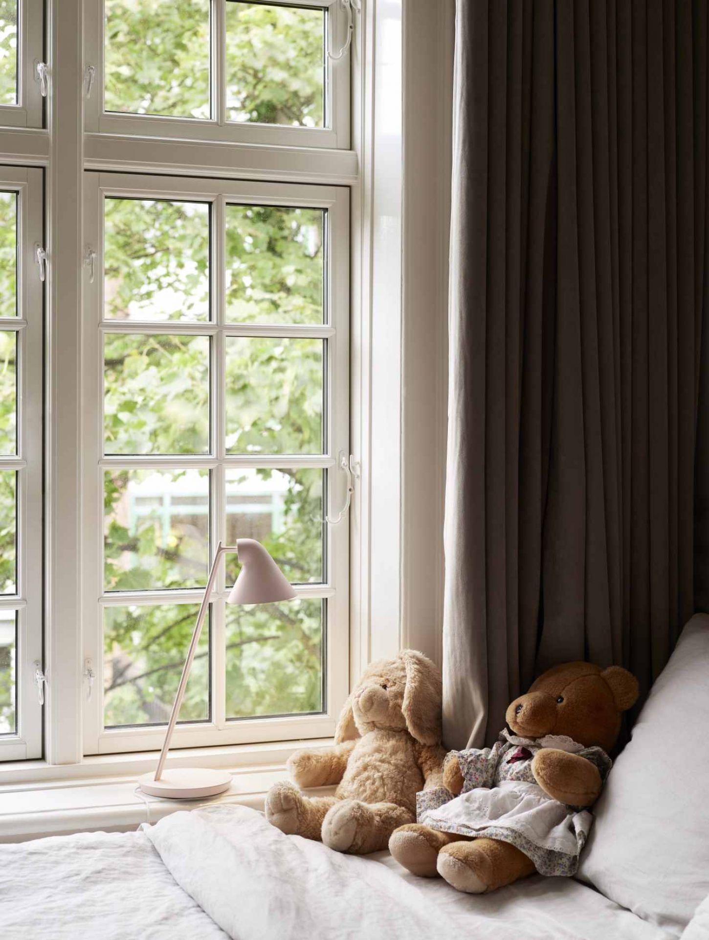 NJP Mini Tischleuchte in Soft Pink auf Fensterbank mit Teddybären und Tageslicht.