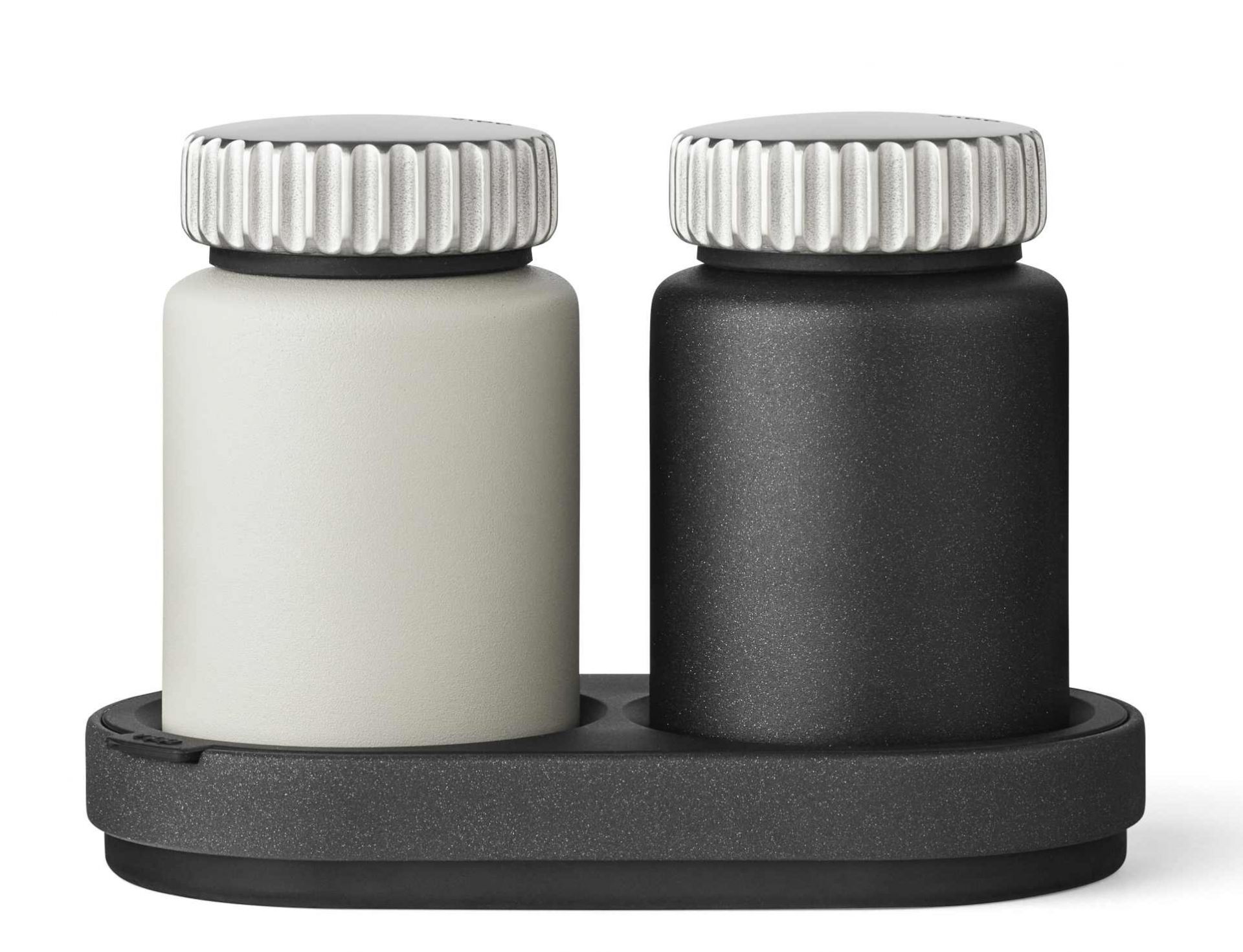 Vipp Salz- und Pfeffermühle Set in Schwarz und Weiß auf einer dunklen Ablage.