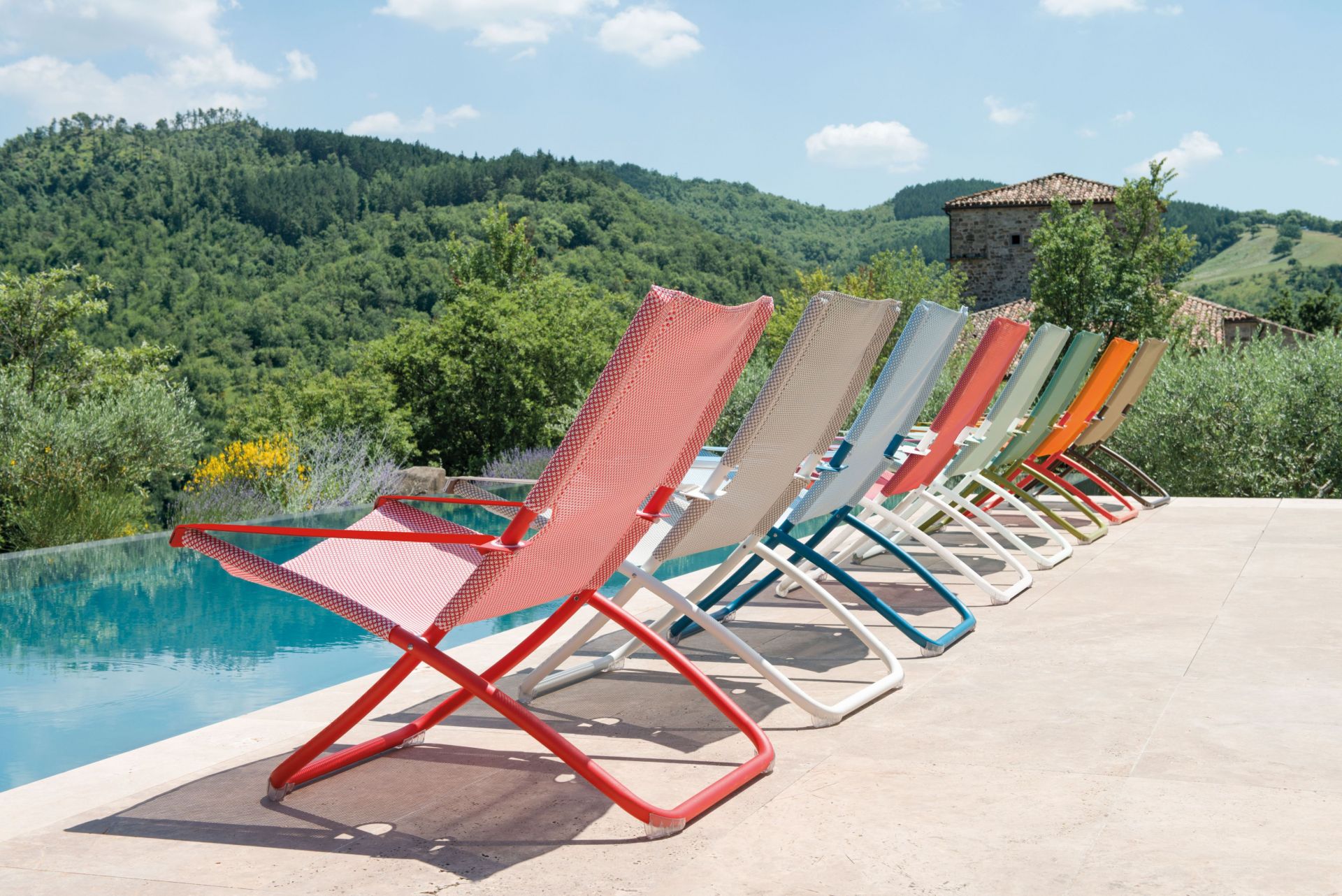 Reihe farbenfroher Emu Snooze Liegestühle am Pool, indianbraun und beige inklusive. Gartenmöbel für entspannte Stunden.