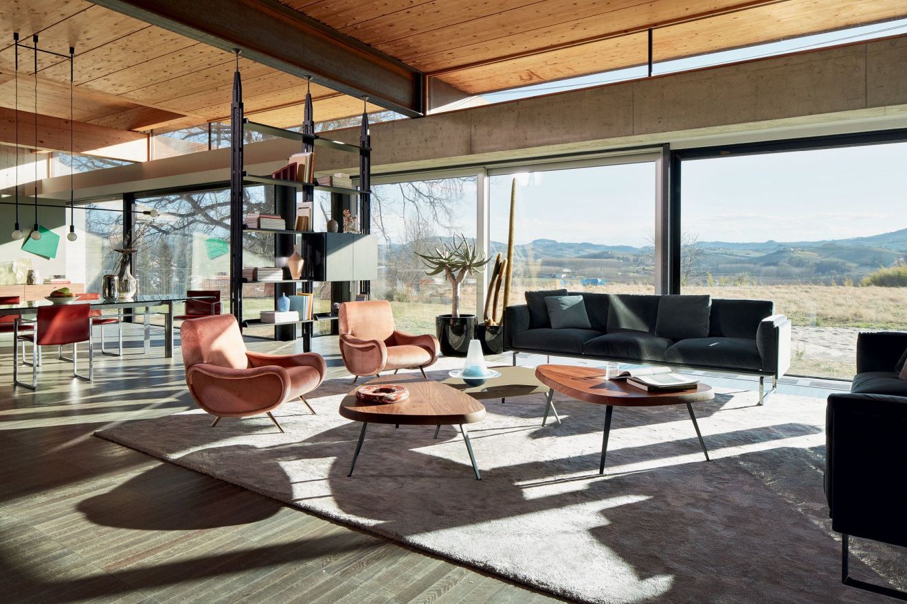 Helles Wohnzimmer mit Cassina Sofa, 3-Sitzer, grauer Polsterung und großem Fenster mit Ausblick.