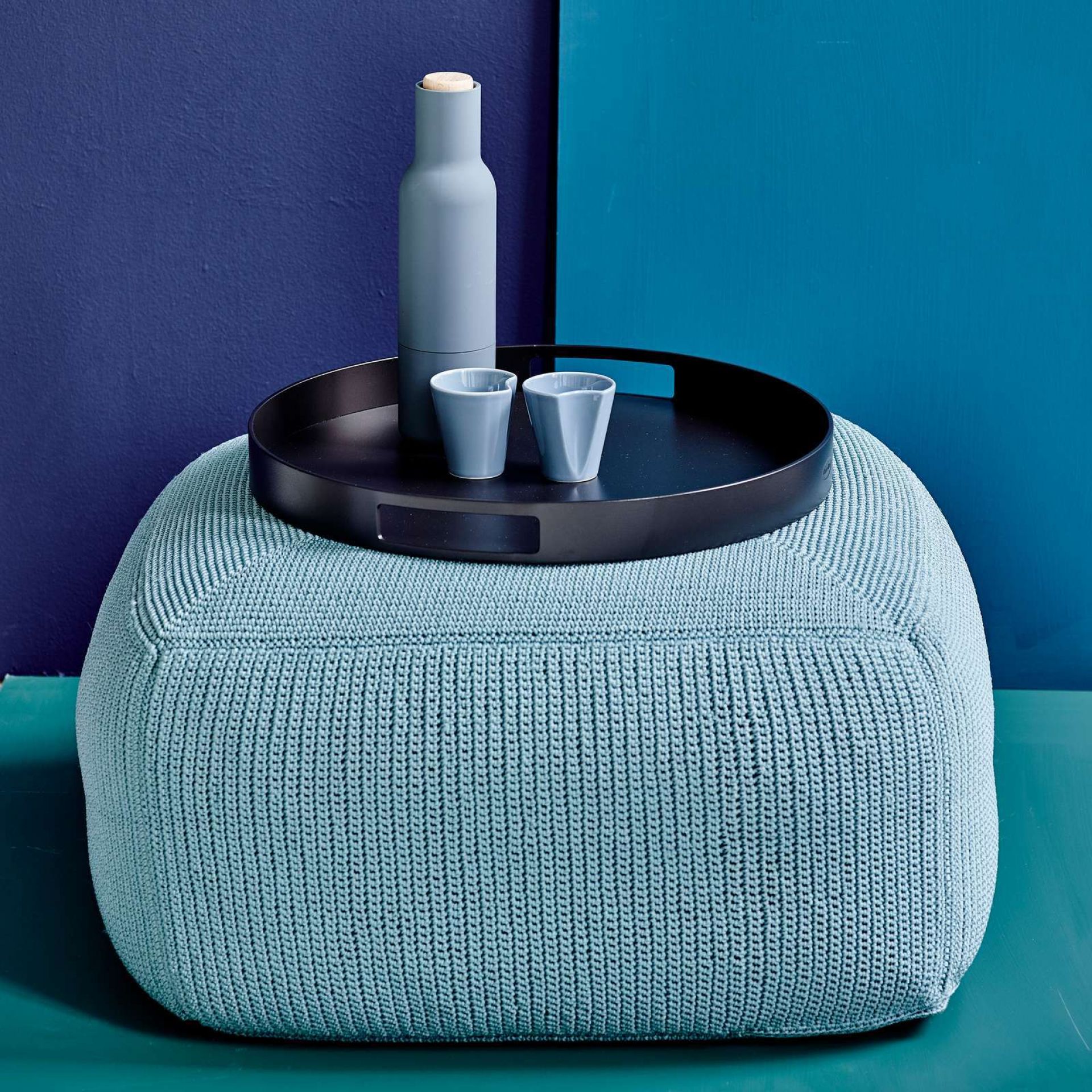 Divine Outdoor Hocker Cane-Line Sand in Hellblau mit Tablett, Flasche und zwei Bechern.