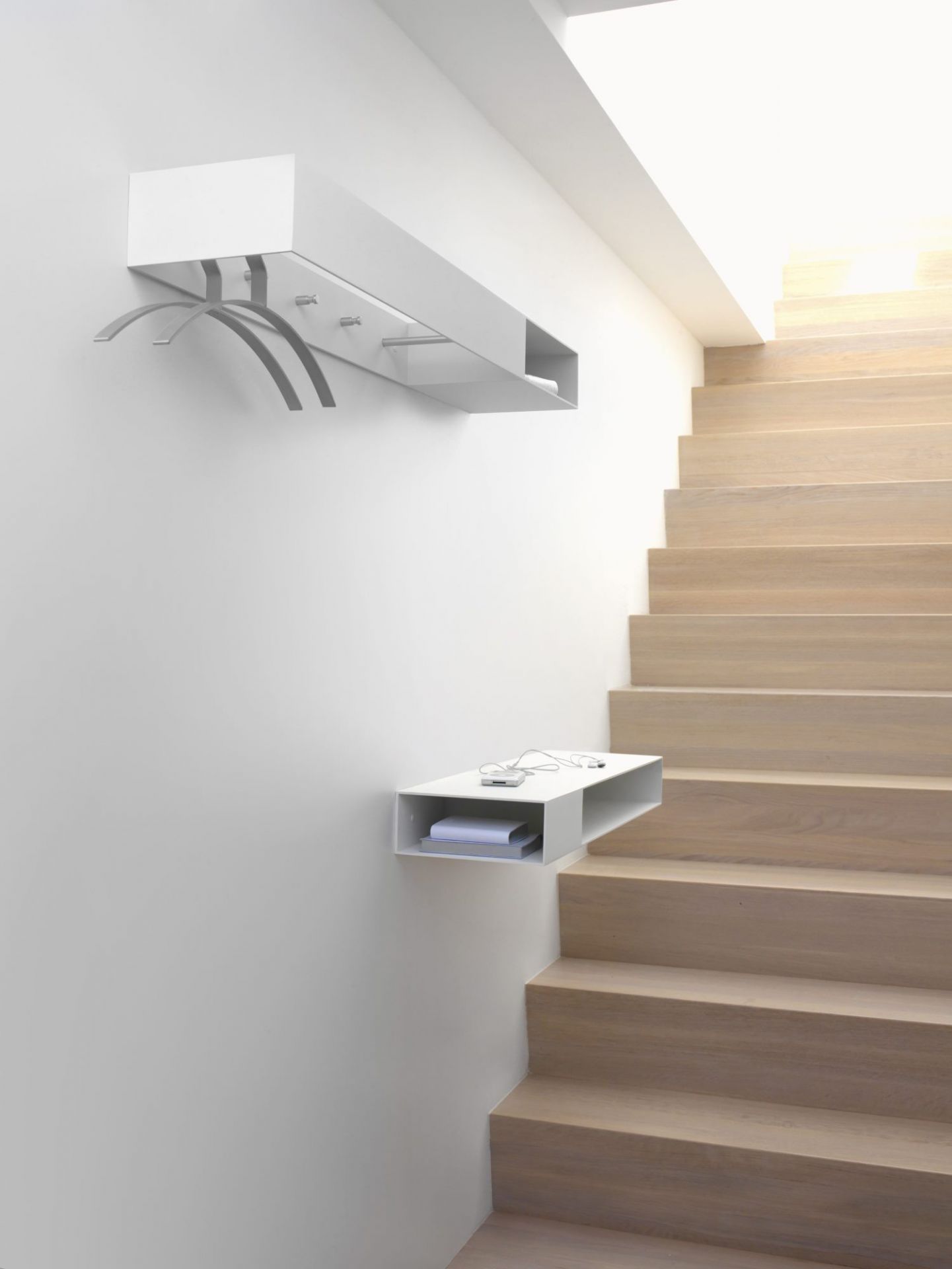Weiße Schönbuch Konsole mit Garderobe und Ablage neben einer Holztreppe. Modernes Flurmöbel für den Eingangsbereich.
