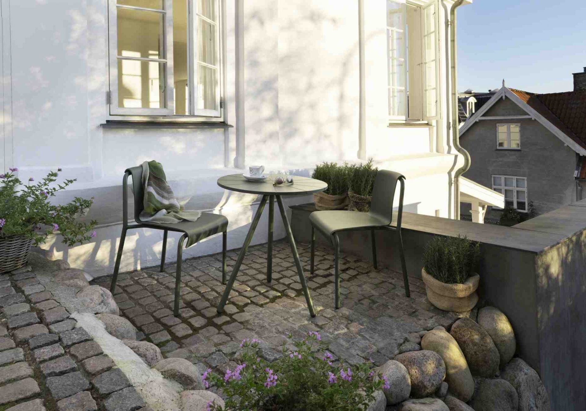 Grüne Nami Dining Chair Outdoor Stühle von Houe mit Tisch auf einer Terrasse.