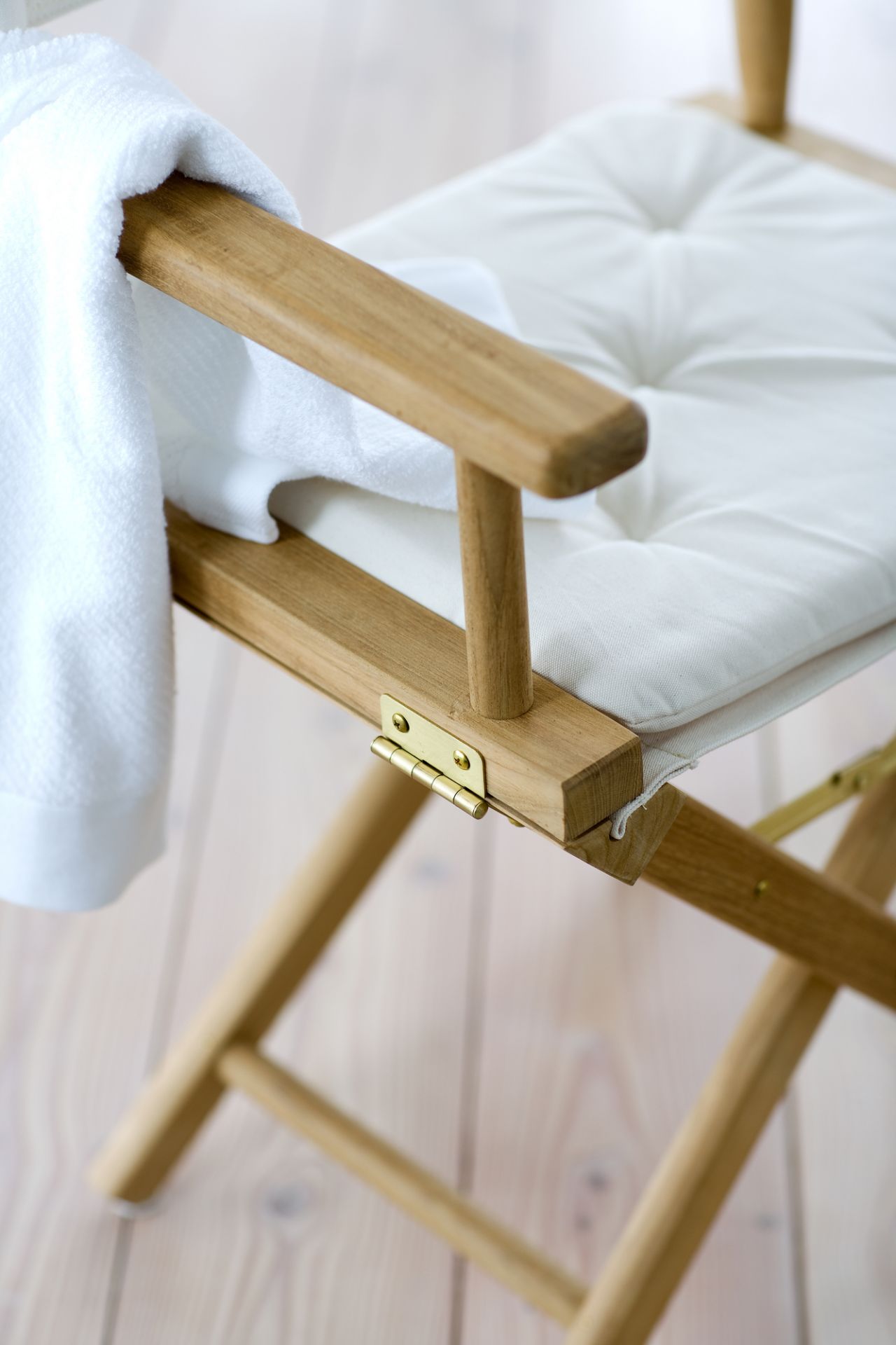 Detailaufnahme des Skagerak Director's Chair Stuhls mit weißem Sitzkissen und Handtuch, geeignet für Indoor und Outdoor.