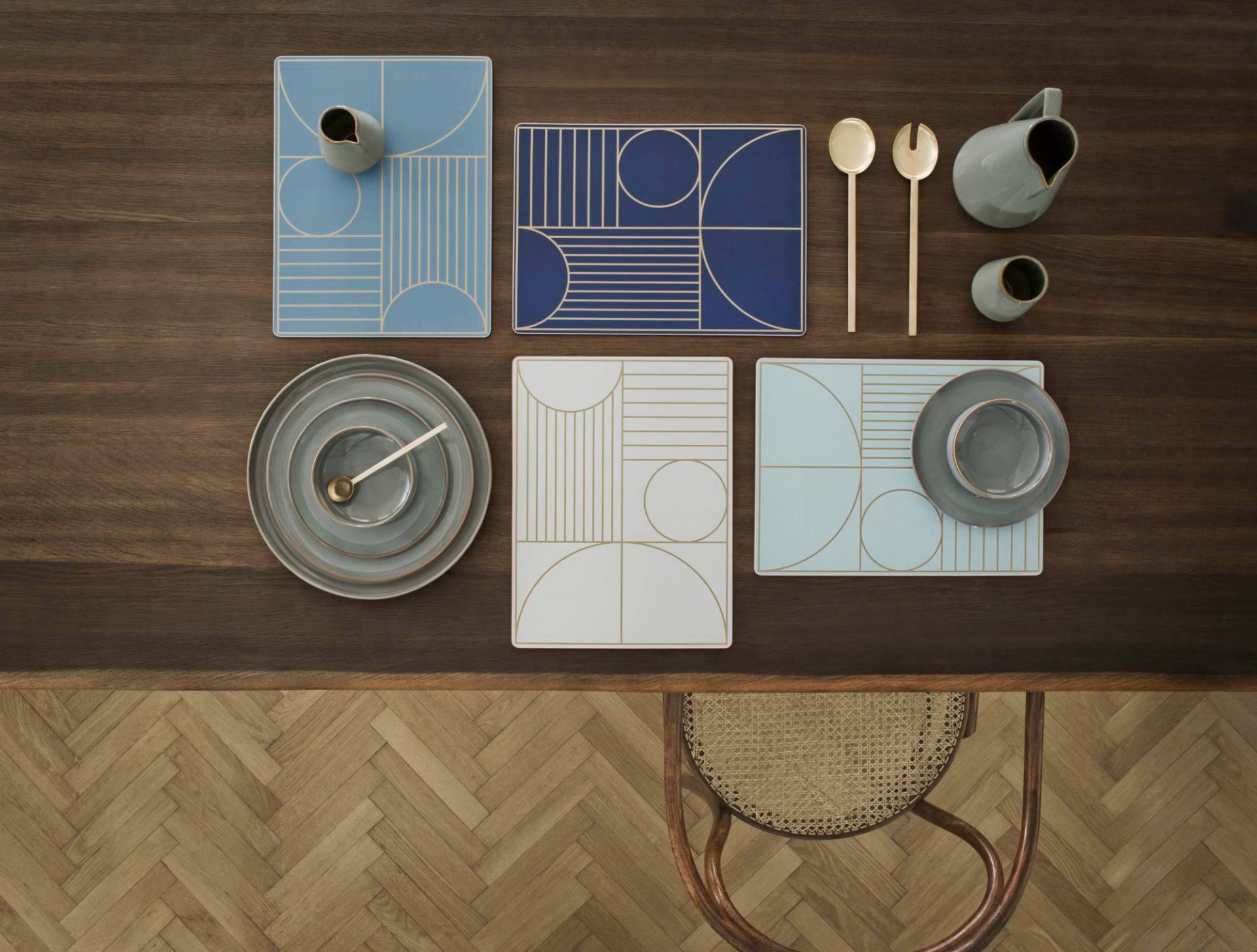 Draufsicht: Ferm Living Salatbesteck, Teller, Krüge und Tischsets auf dunklem Holztisch.