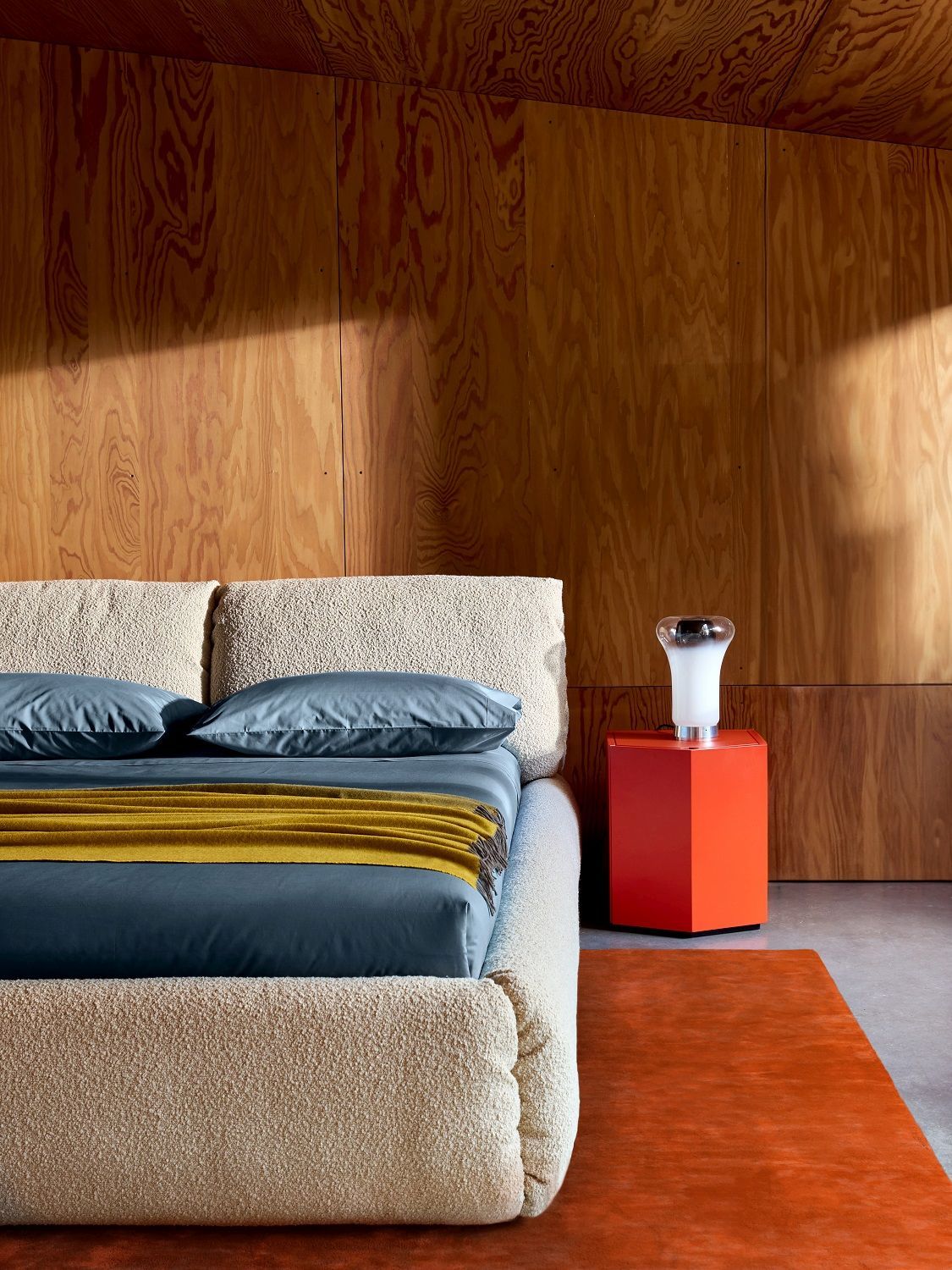 Zanotta Nachttisch Z24 Nightstand 728 in roter Farbe neben einem Bett mit Textilbezug.