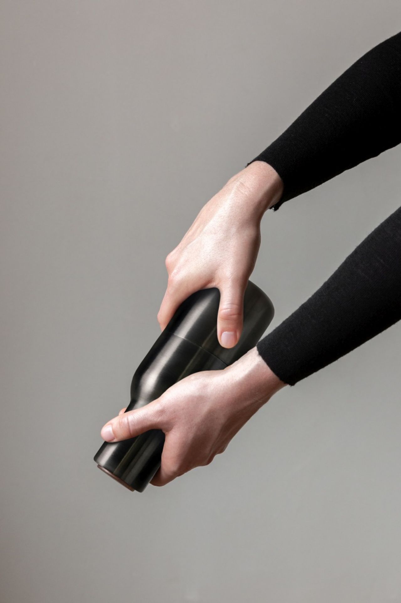 Hände bedienen Audo Bottle Grinder, bronzierte Messing Salz- und Pfeffermühle für stilvolles Würzen.