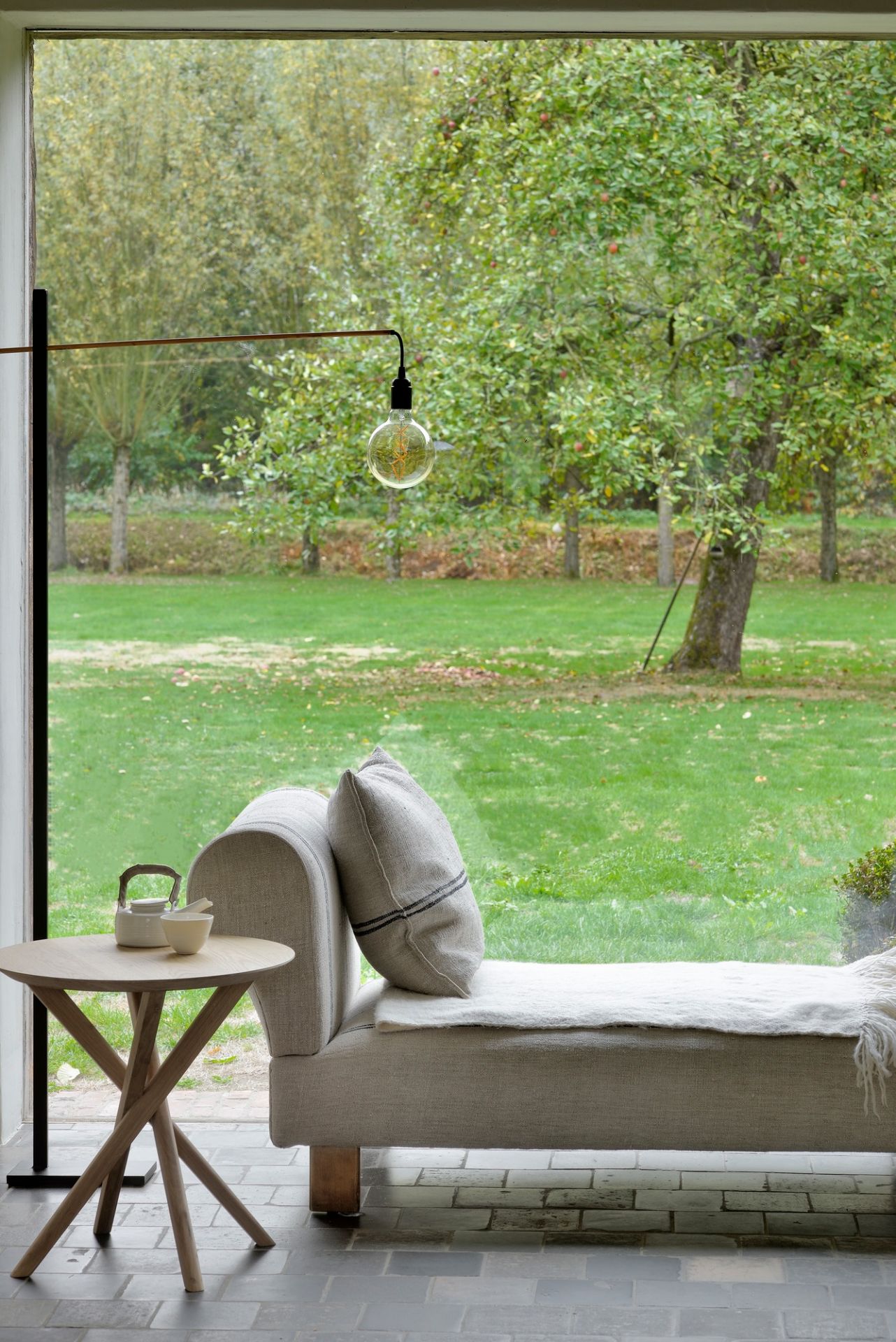 Mikado Beistelltisch Eiche von Ethnicraft neben einer Fensterbank mit Blick in den Garten.