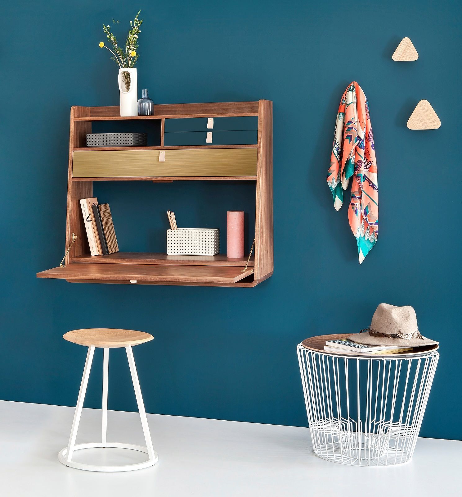 Gaston Wandsekretär aus Walnuss und Petrolblau an blauer Wand, mit Hocker und Beistelltisch.