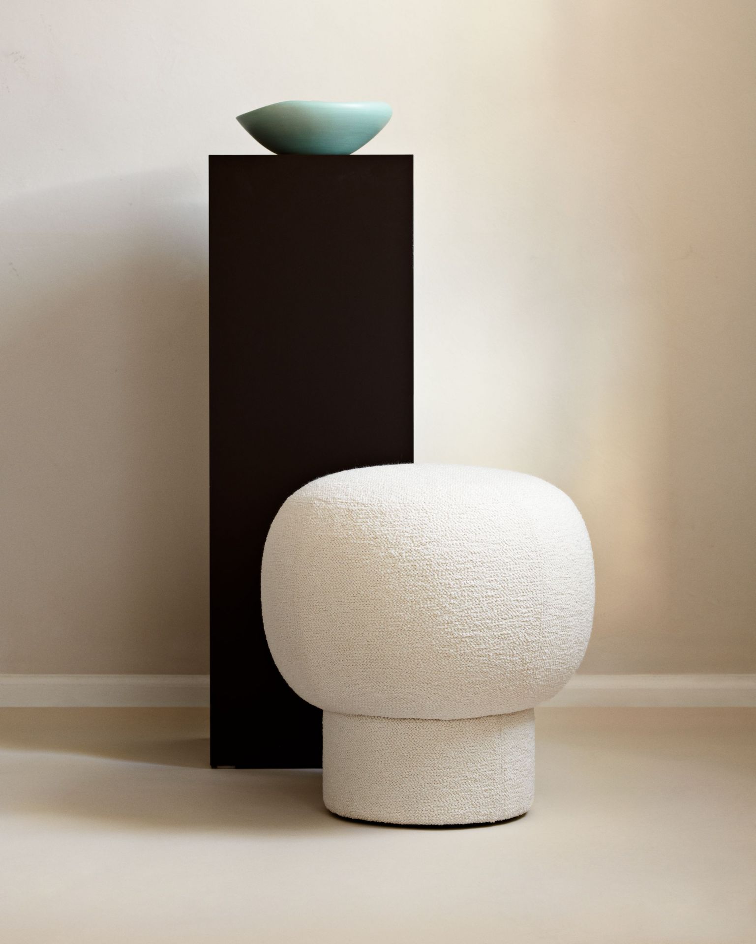 Weißer Liége Pouf von Norr11 neben schwarzem Podest mit türkiser Schale für modernes Wohnen.