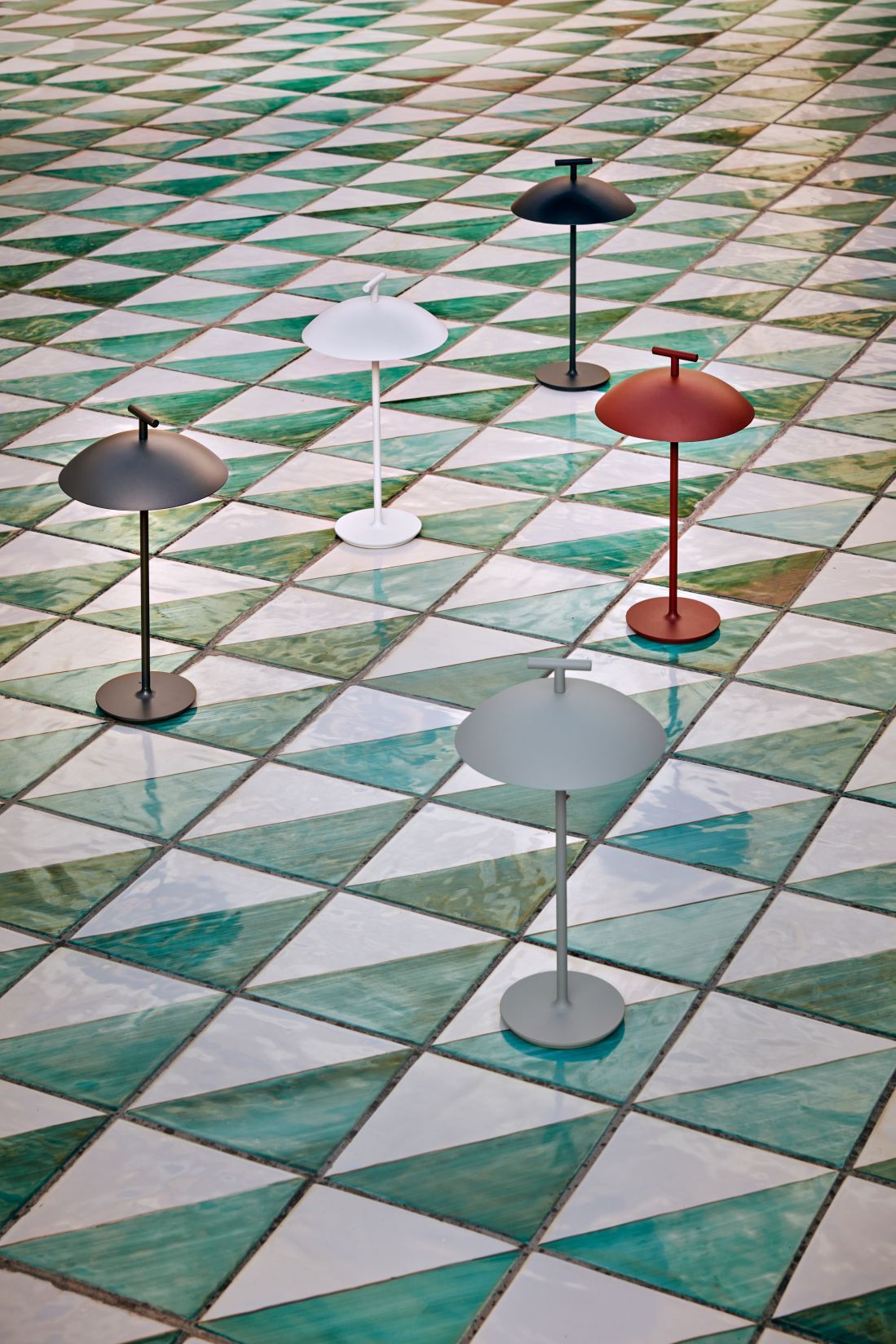 Mehrere Mini Geen-A Tischlampen von Kartell in verschiedenen Farben auf gemustertem Boden.