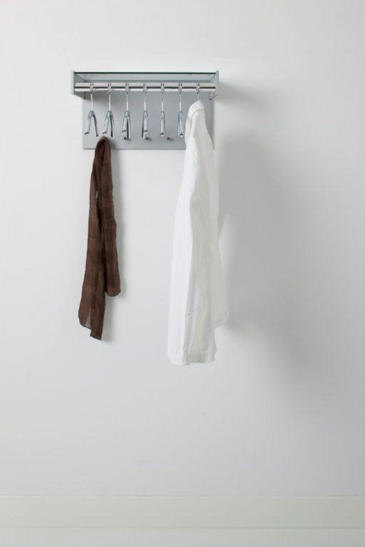 Hangon Wandgarderobe mit Kleiderbügeln, Schal und Hemd an einer grauen Wand. Moderne Garderobenlösung.