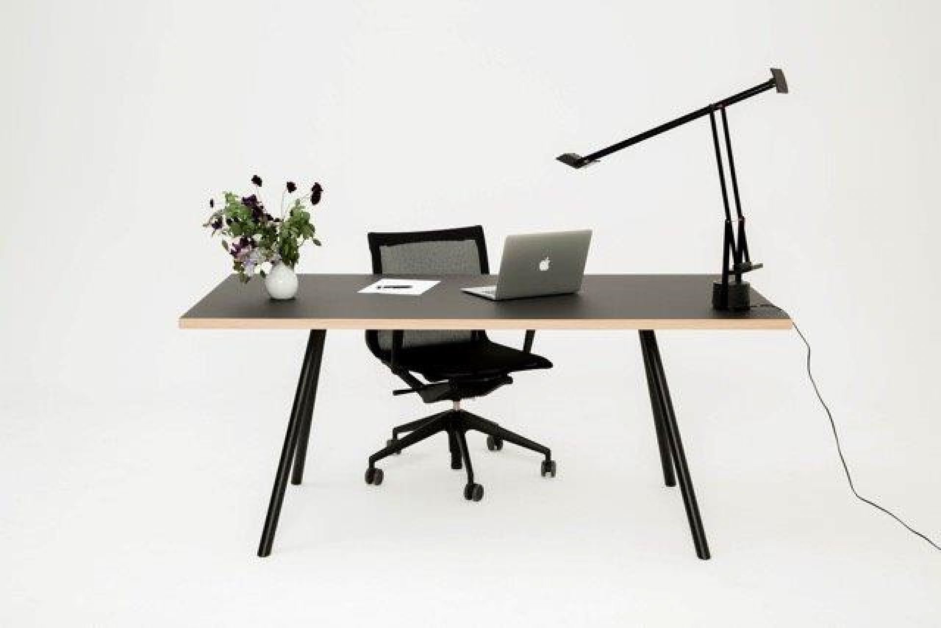 Schwarzer Schreibtisch mit Stahlgestell von New Tendency, Laptop, Lampe und Bürostuhl vor weißem Hintergrund.