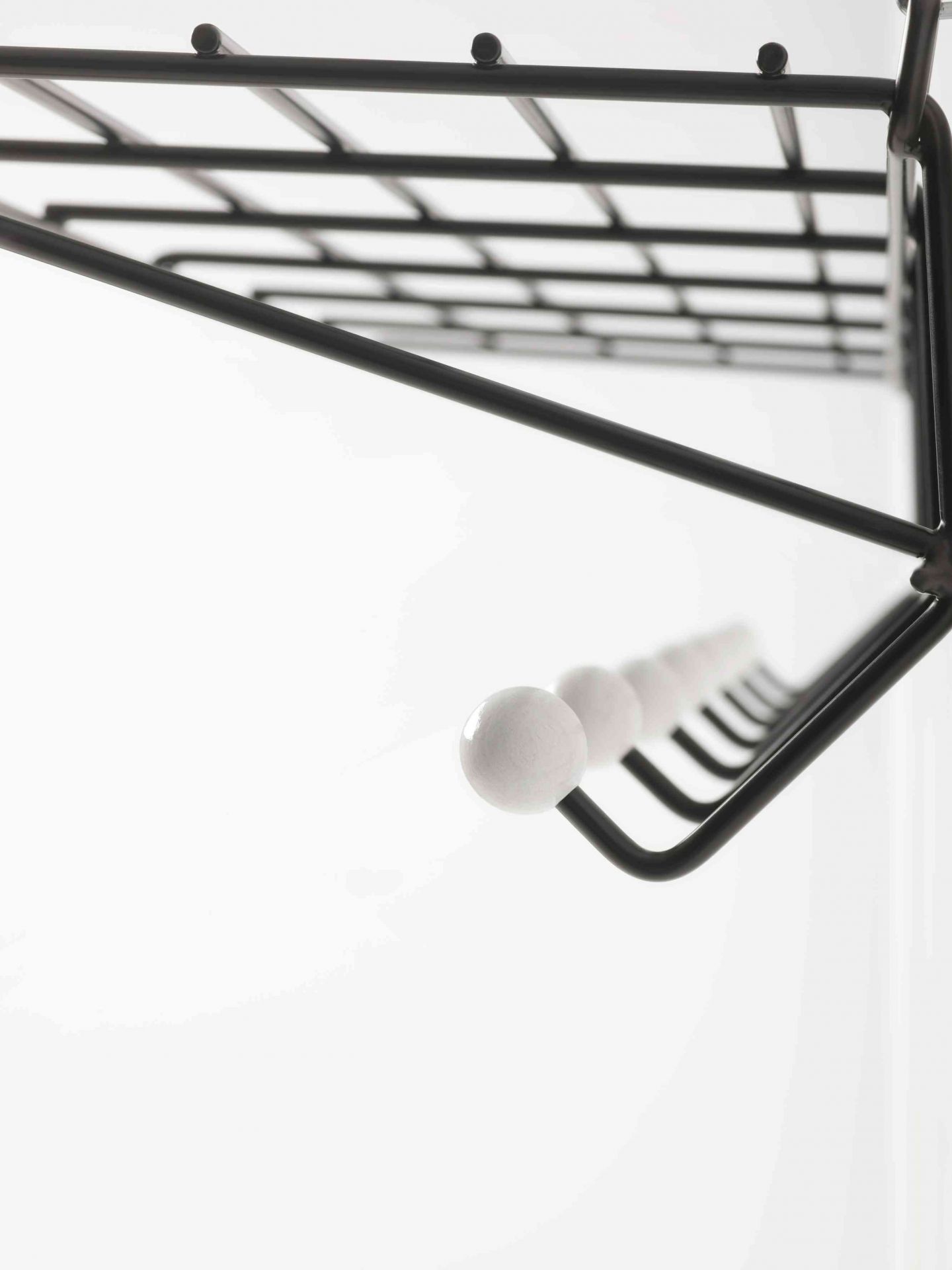 Detailaufnahme der DZ 05 Garderobe Spectrum: Schwarzes Metallgestell mit weißen Knaufhaken und Ablagegitter.