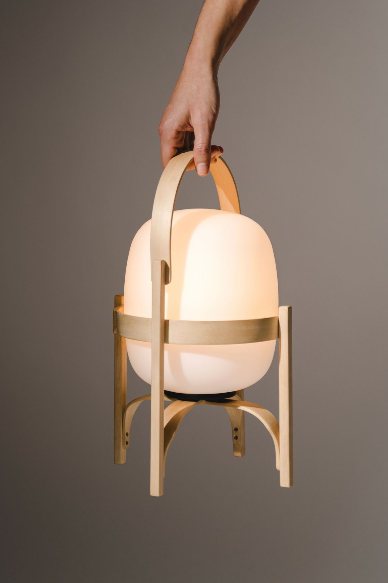 Hand hält Cestita Tischleuchte mit Opal Kunststoffschirm, moderne Tischlaterne für stimmungsvolle Beleuchtung.