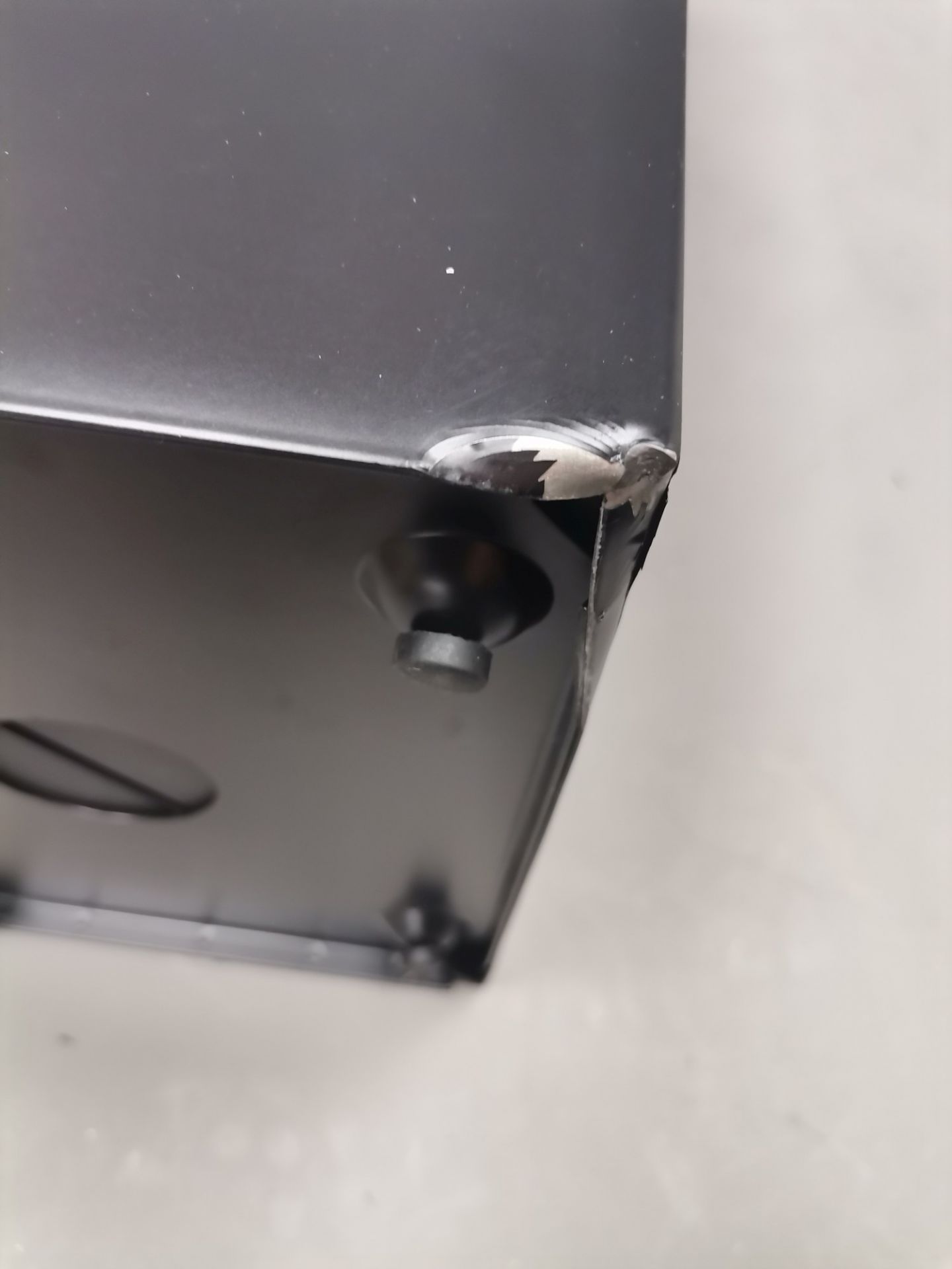 Detailaufnahme: Beschädigung an der Ecke des schwarzen Via Schirmständers, ein Mängelexemplar mit Lackschäden.