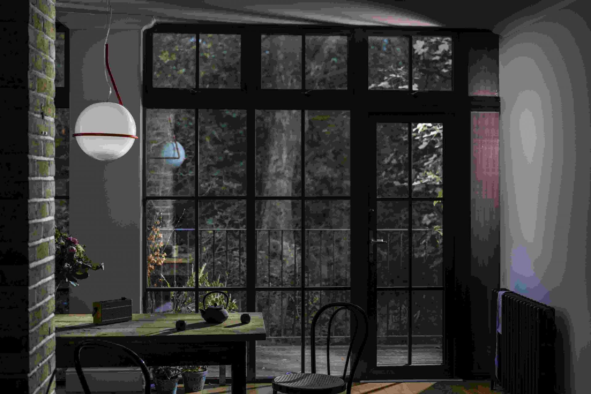 Innenaufnahme mit der runden Tonda Pendelleuchte von Foscarini in Weiß mit orangem Detail über einem Esstisch.