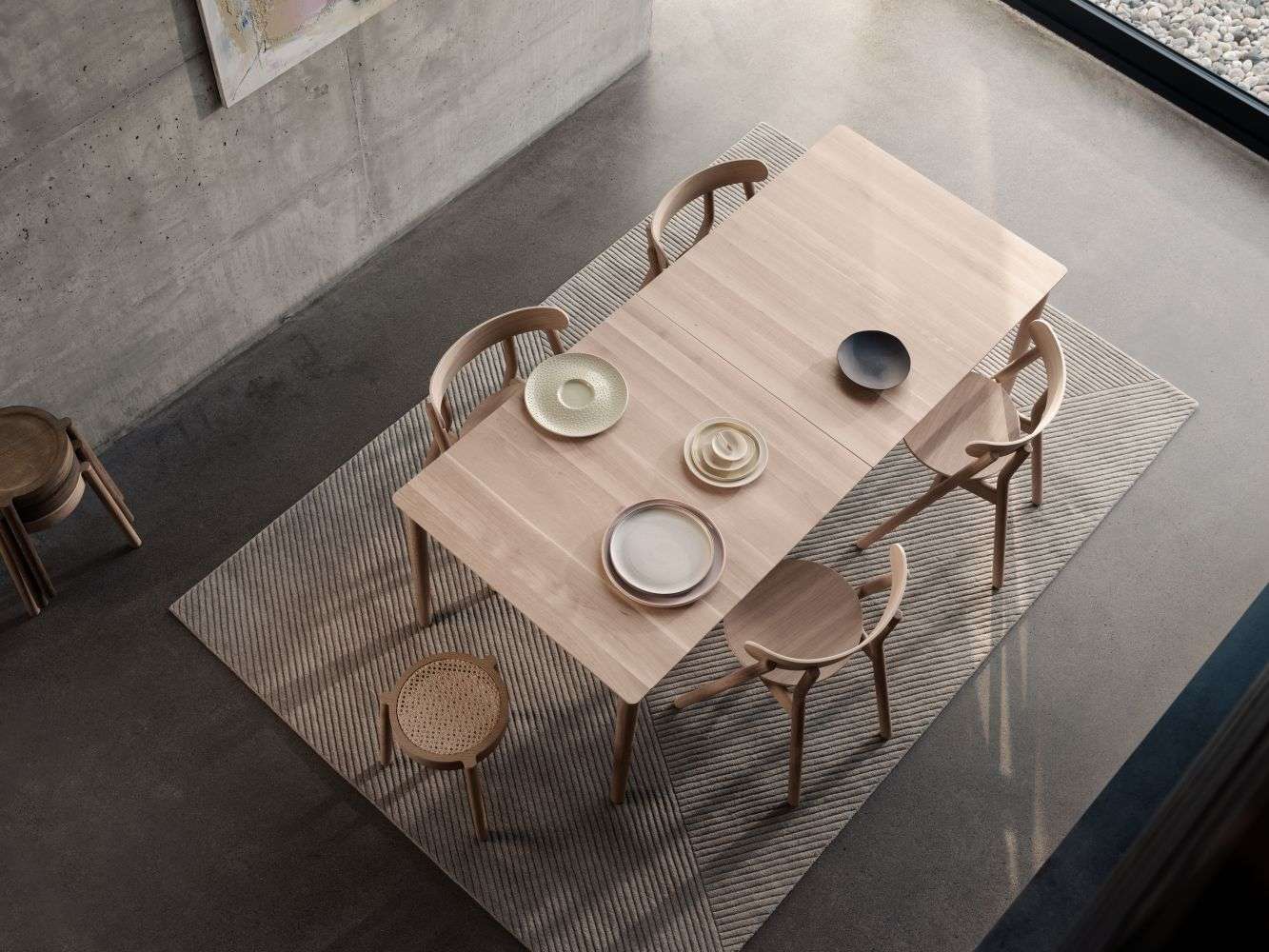 Expand Dining table von Northern, ein heller Holztisch mit Stühlen und Geschirr, Draufsicht.