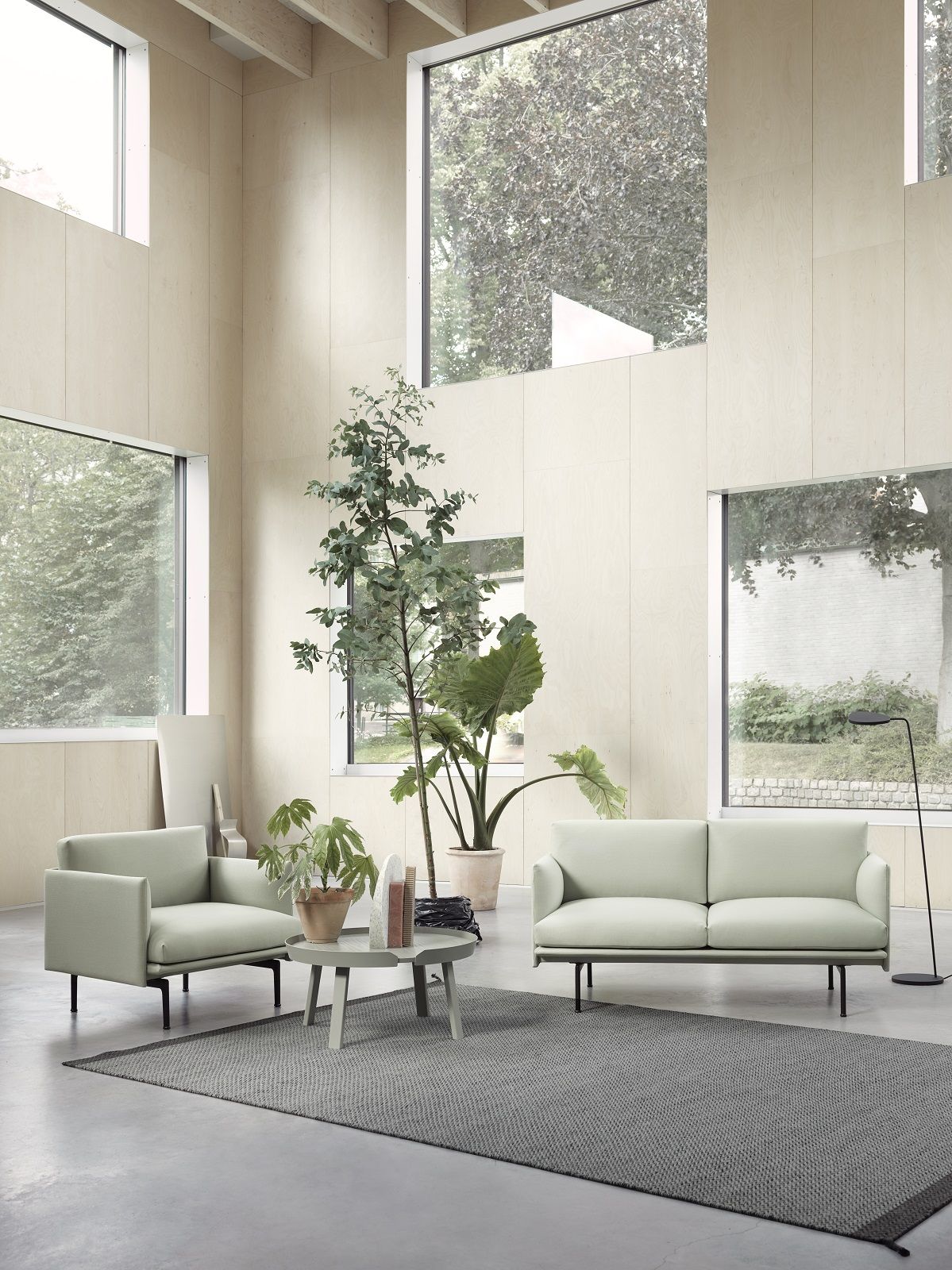 Helles Wohnzimmer mit Muuto Outline Sofa und Sessel in Mintgrün auf grauem Teppich.