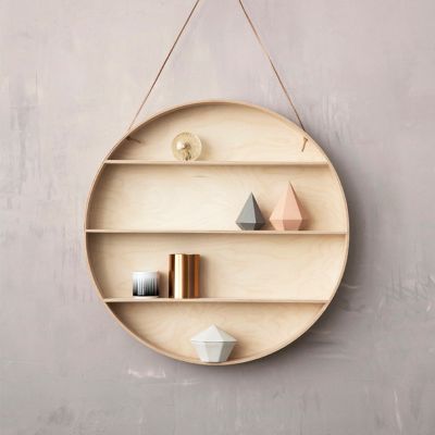 The Round Dorm Hängeregal von Ferm Living, ein rundes Holzregal mit Lederband an einer grauen Wand.