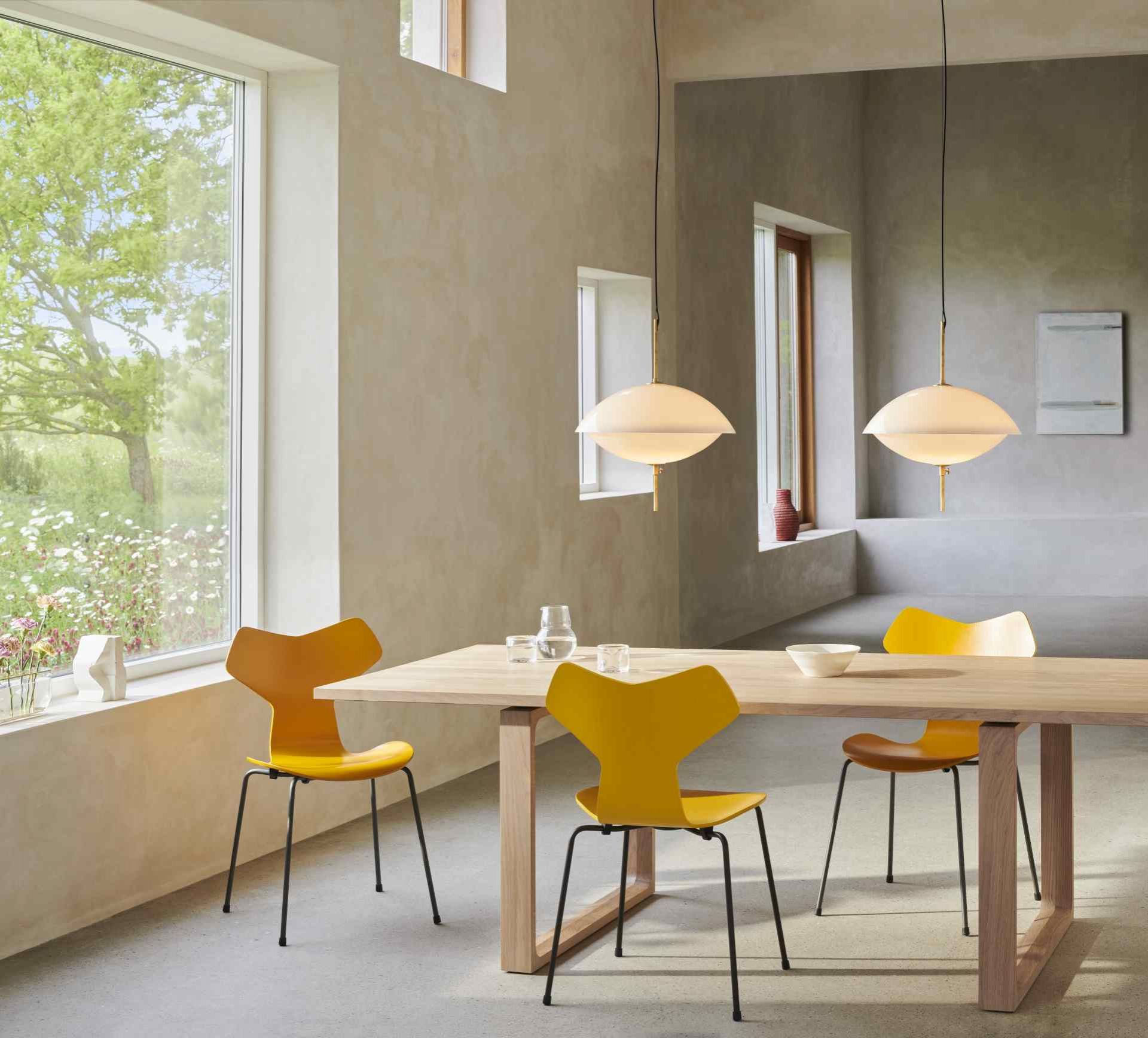 Esszimmer mit Fritz Hansen Clam Pendelleuchten, Design-Hängeleuchten in Weiß über einem Holztisch.