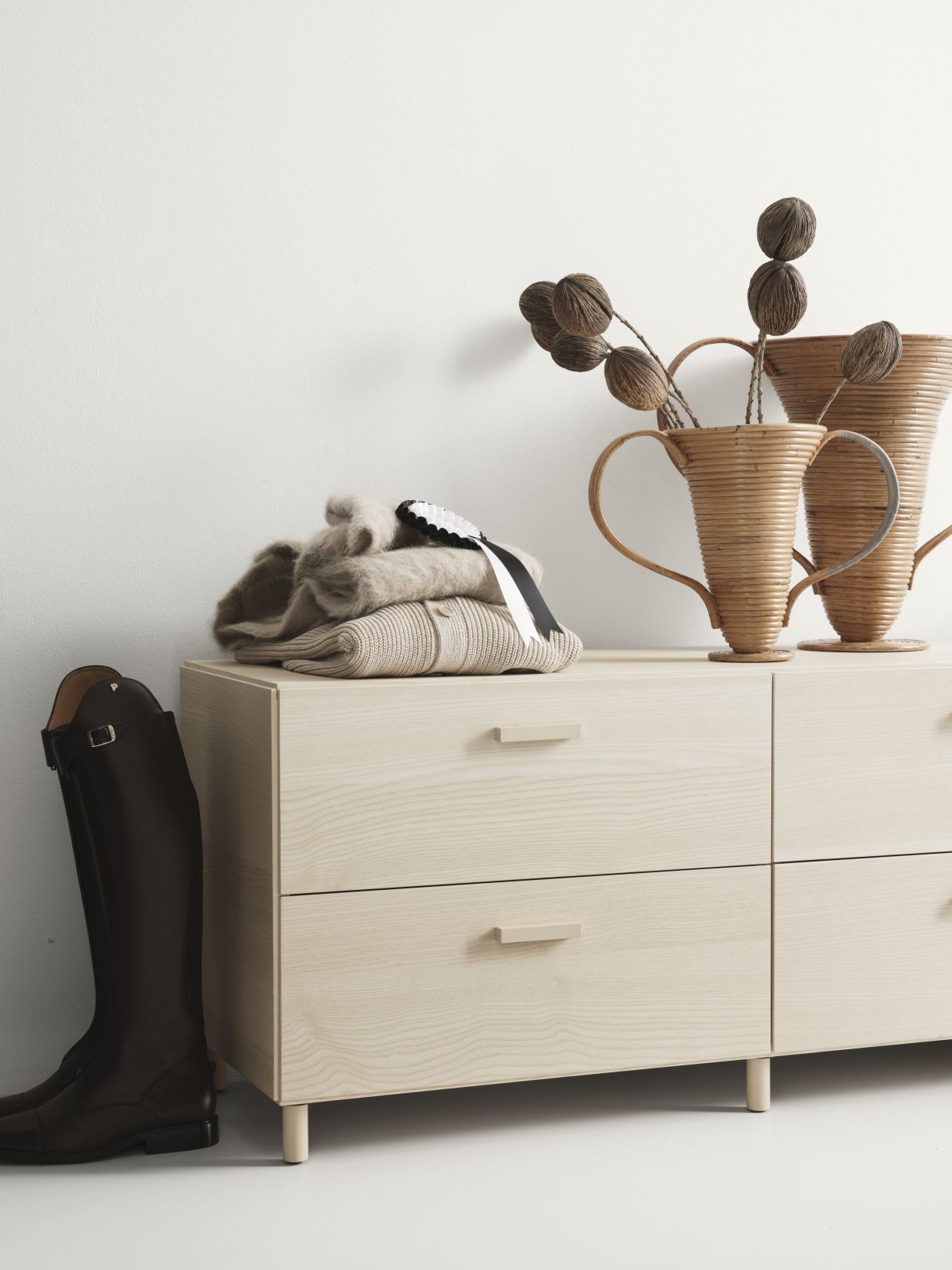 Relief Kommode niedrig von String Furniture aus Esche mit Kleidung und Dekoration.