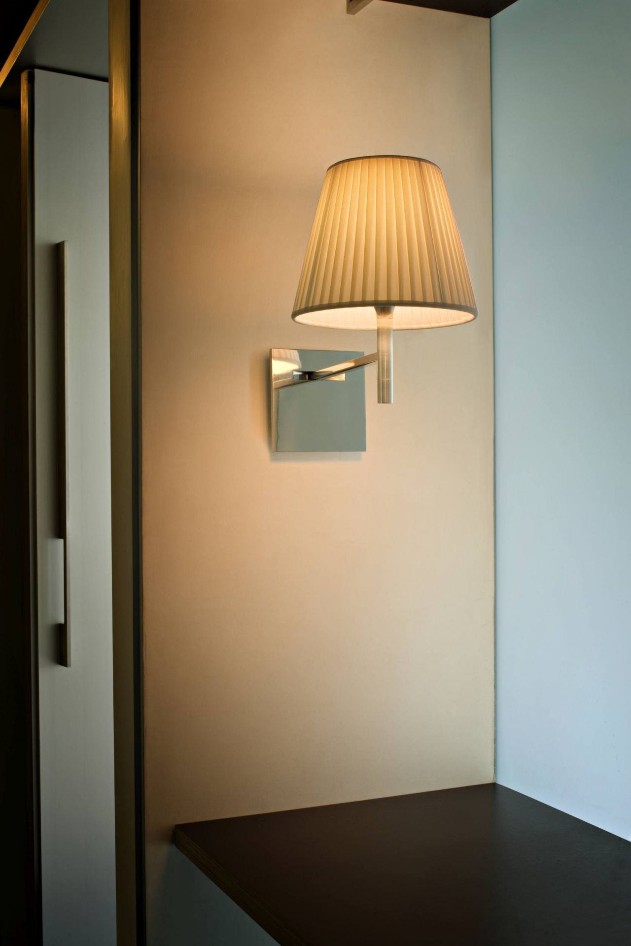 Nahaufnahme der Ktribe Wandleuchte von Flos mit plissiertem Schirm und Chrom-Wandhalterung.