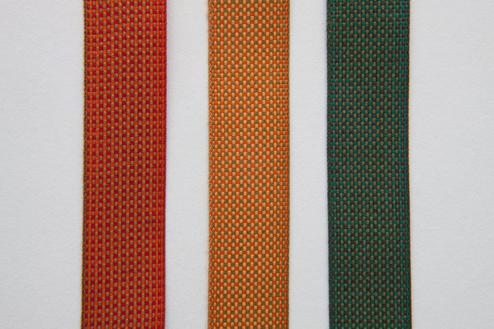 Nahaufnahme von drei Stoffstreifen in Rot, Orange und Grün für Santa & Cole Leuchten.