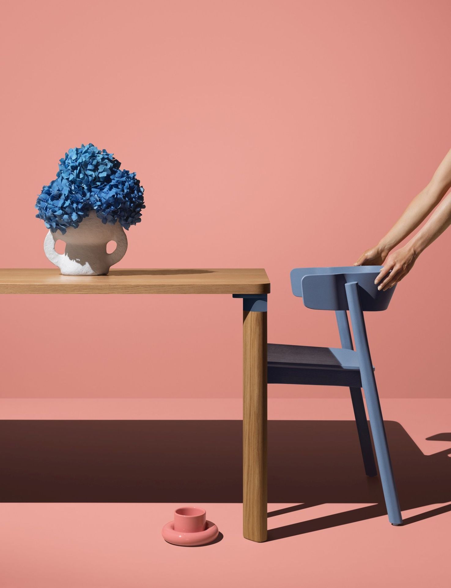 Enfold Chair Stuhl von Mizetto in Blau, neben Holztisch mit blauen Hortensien.