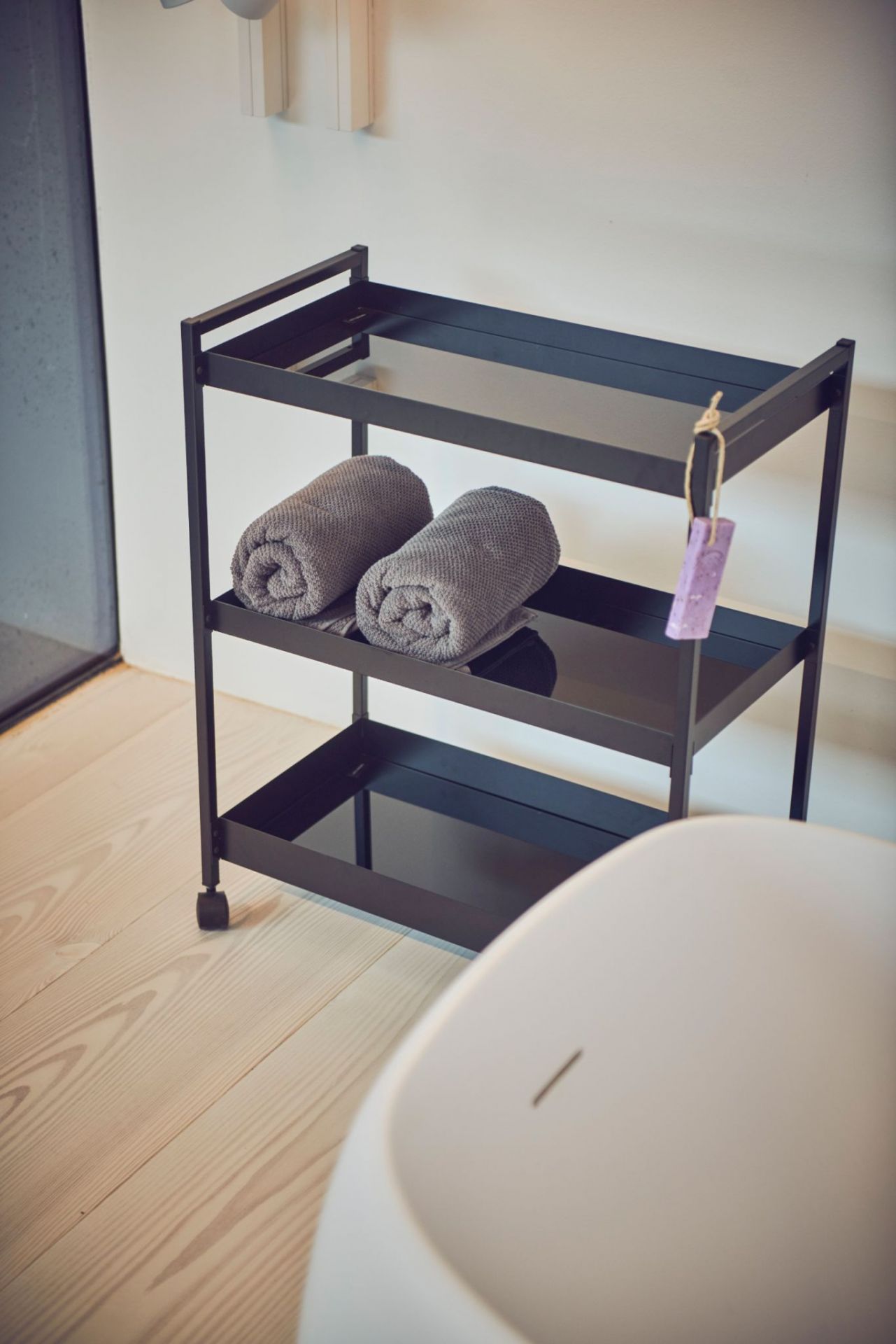 Schwarzer Butler Servierwagen von Jan Kurtz mit Handtüchern und drei Ablageflächen im Badezimmer.
