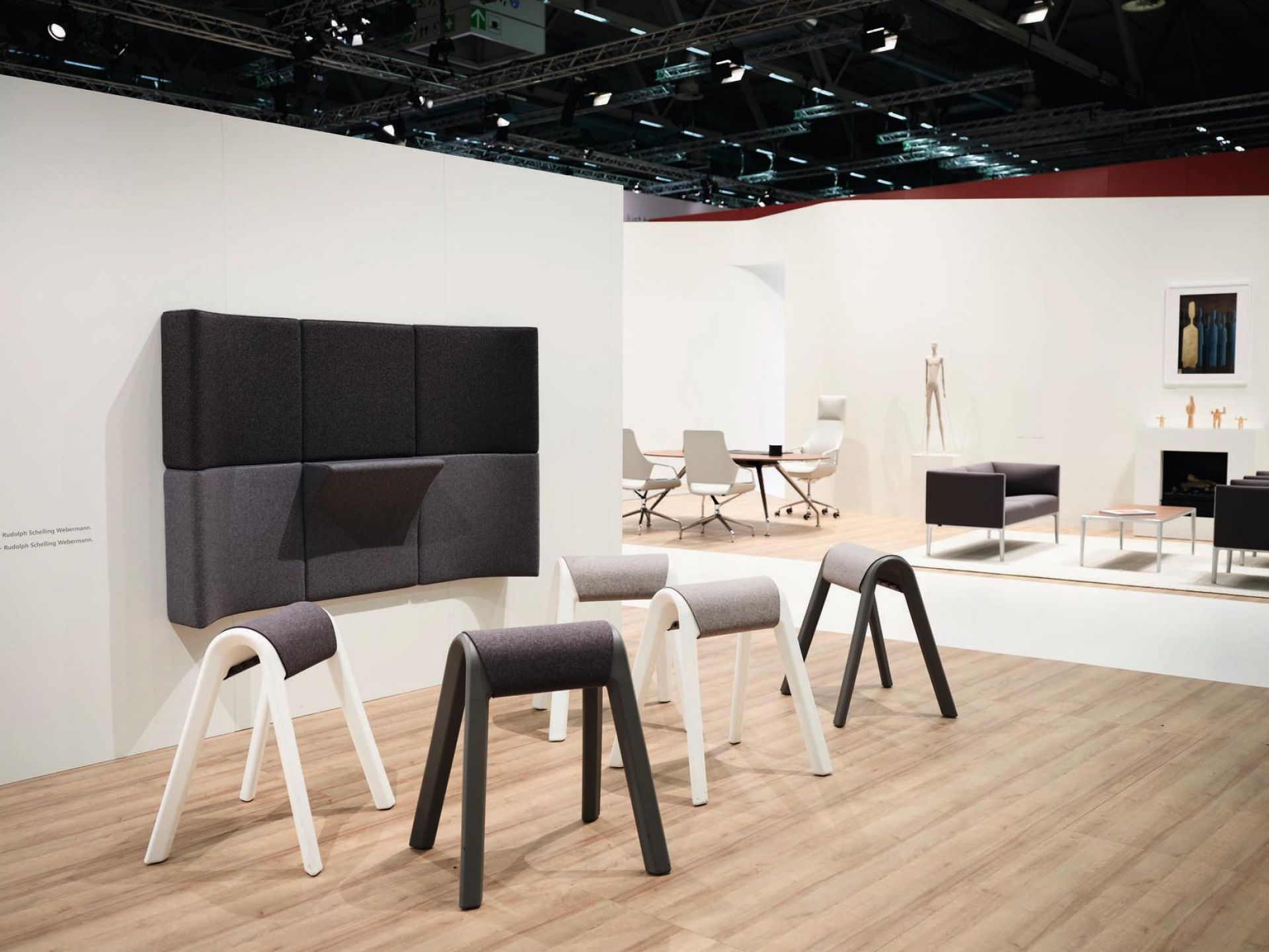 Anthrazitfarbene Sitzauflagen von Wilkhahn Programm 204 auf einer Messe, moderne Büromöbel und Designelemente im Hintergrund.